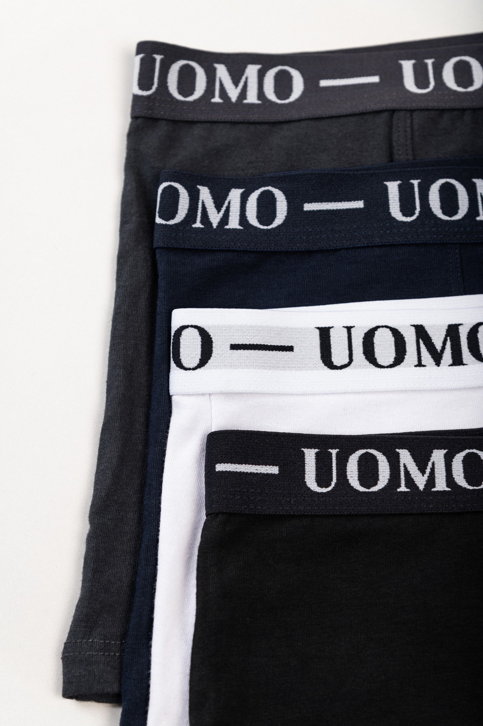 Komplet štirih moških bokser hlačk v belih, sivih, črnih in temno modrih barvah, izdelan iz bombaža in elastana.