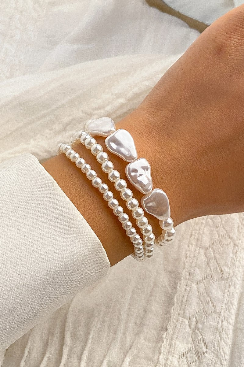 Komplet treh elegantnih zapestnic iz umetnih perlic v beli barvi, zaprtih s kovinskim karabinom.