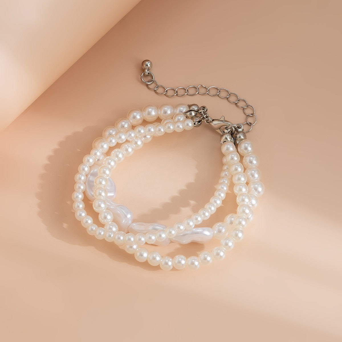 Komplet treh elegantnih zapestnic iz umetnih perlic v beli barvi, zaprtih s kovinskim karabinom.