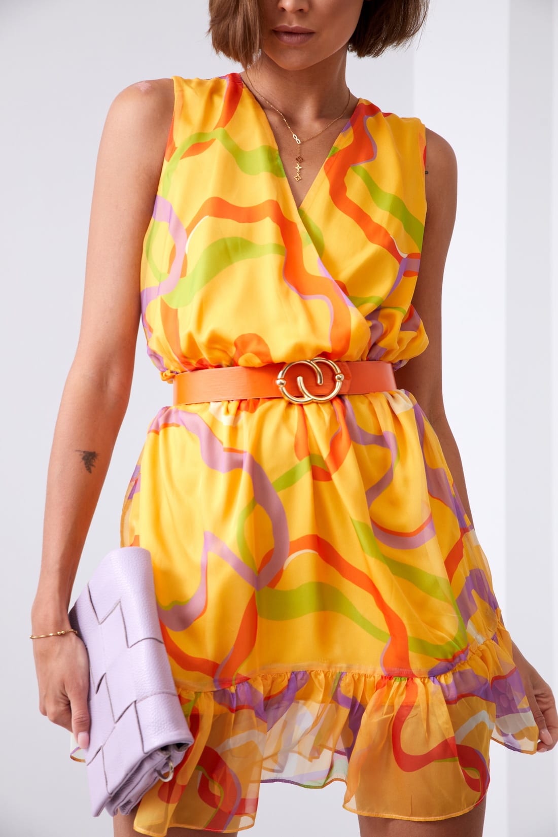 Light patterned dress in saffron and lilac with ruffles and a belt, showcasing its elegant design and vibrant colors.