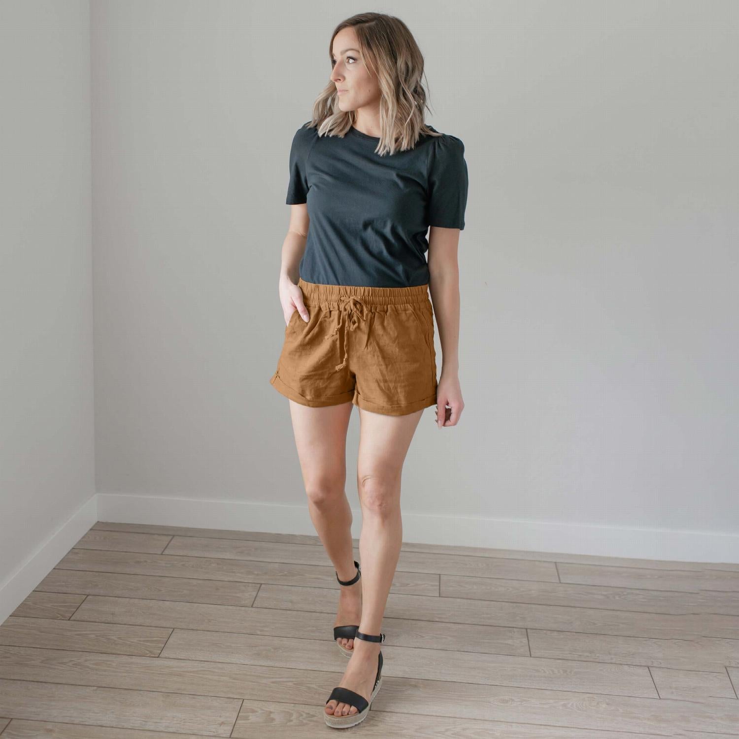 A pair of stylish linen drawstring-waist shorts with pockets, featuring cuffs at the leg openings, displayed in a vibrant color.