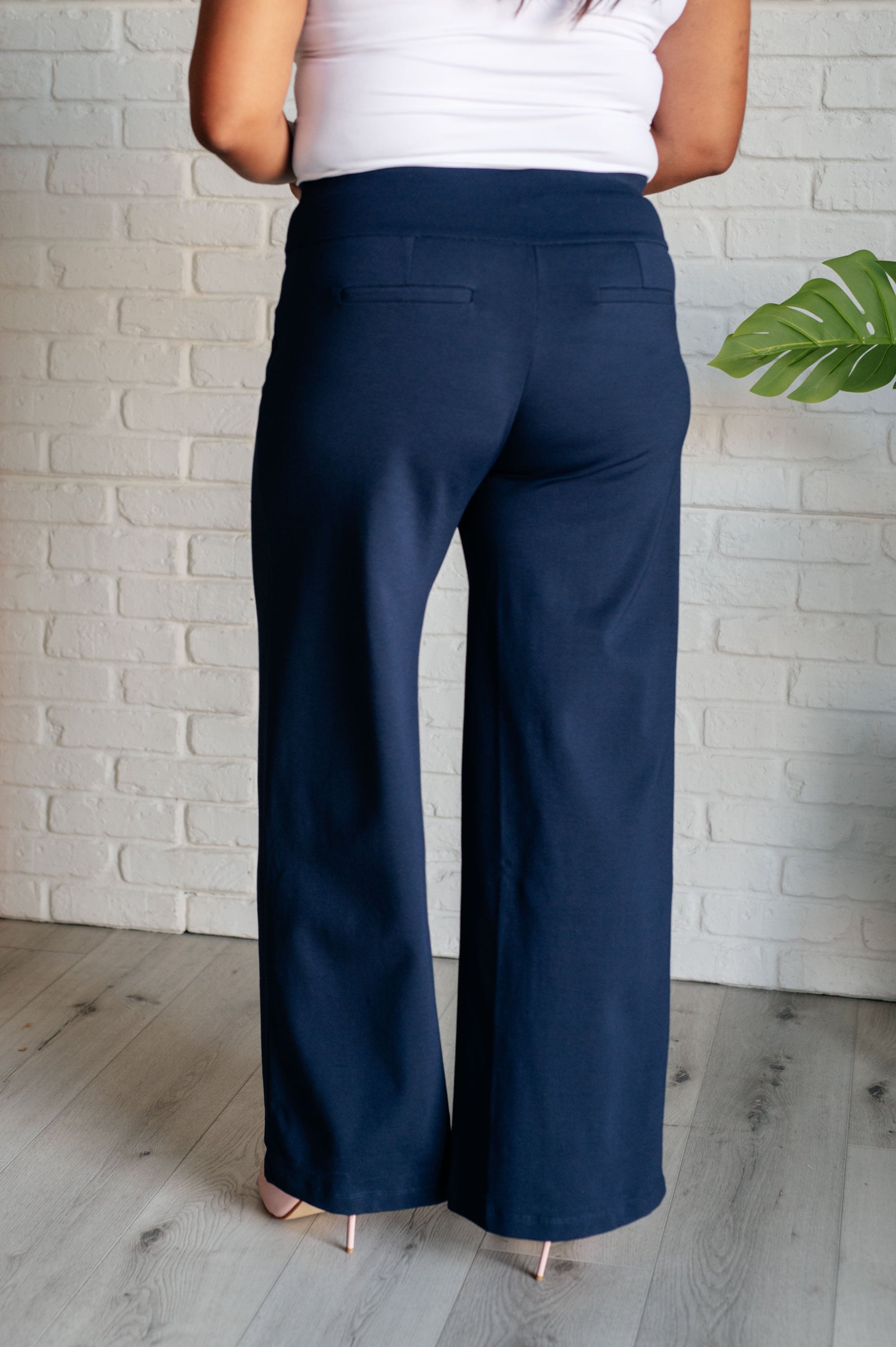 A pair of navy Magic Wide Leg Pants made from high stretch ponte knit fabric, featuring a wide leg design and faux welt pocket.