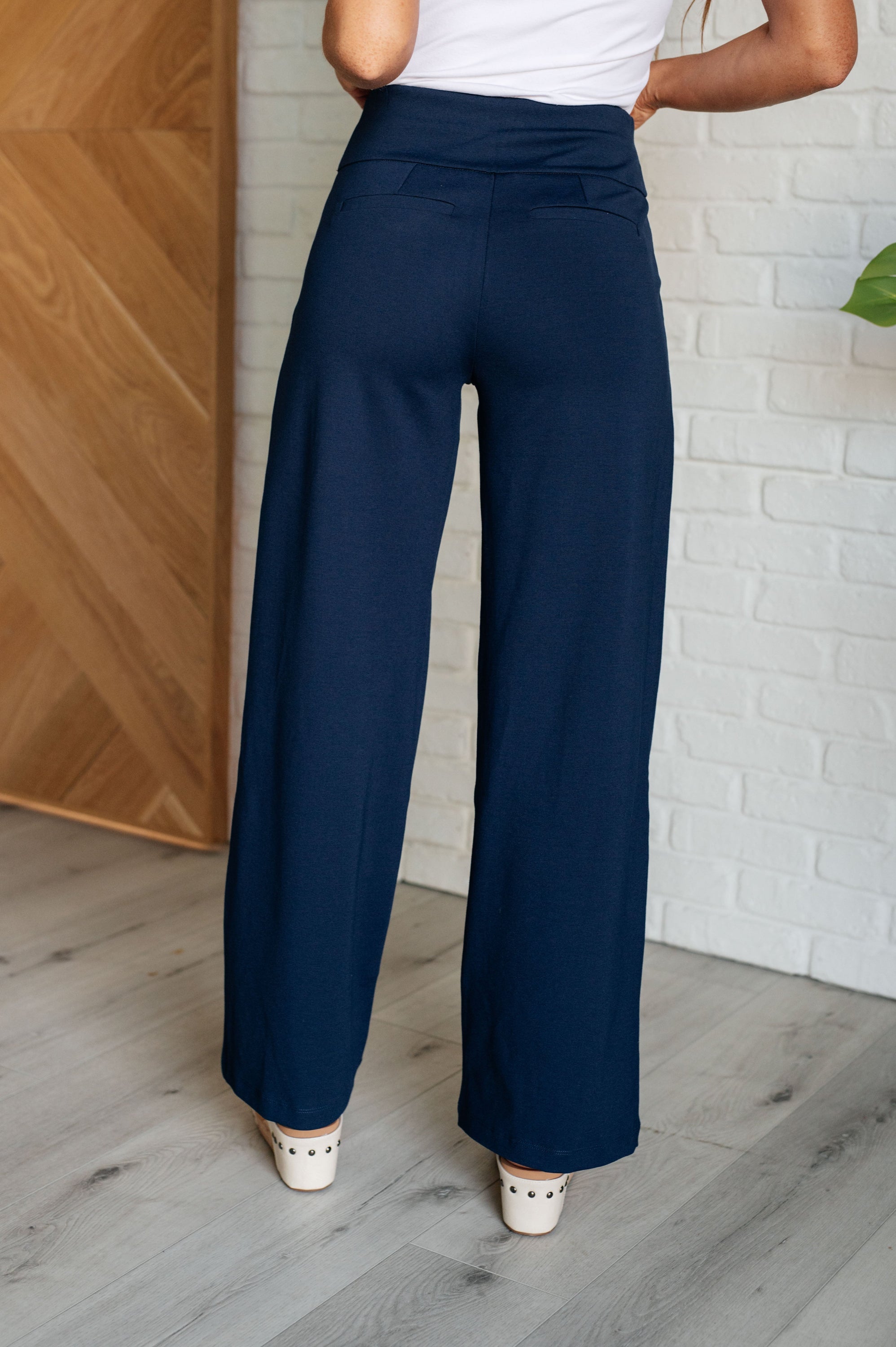 A pair of navy Magic Wide Leg Pants made from high stretch ponte knit fabric, featuring a wide leg design and faux welt pocket.