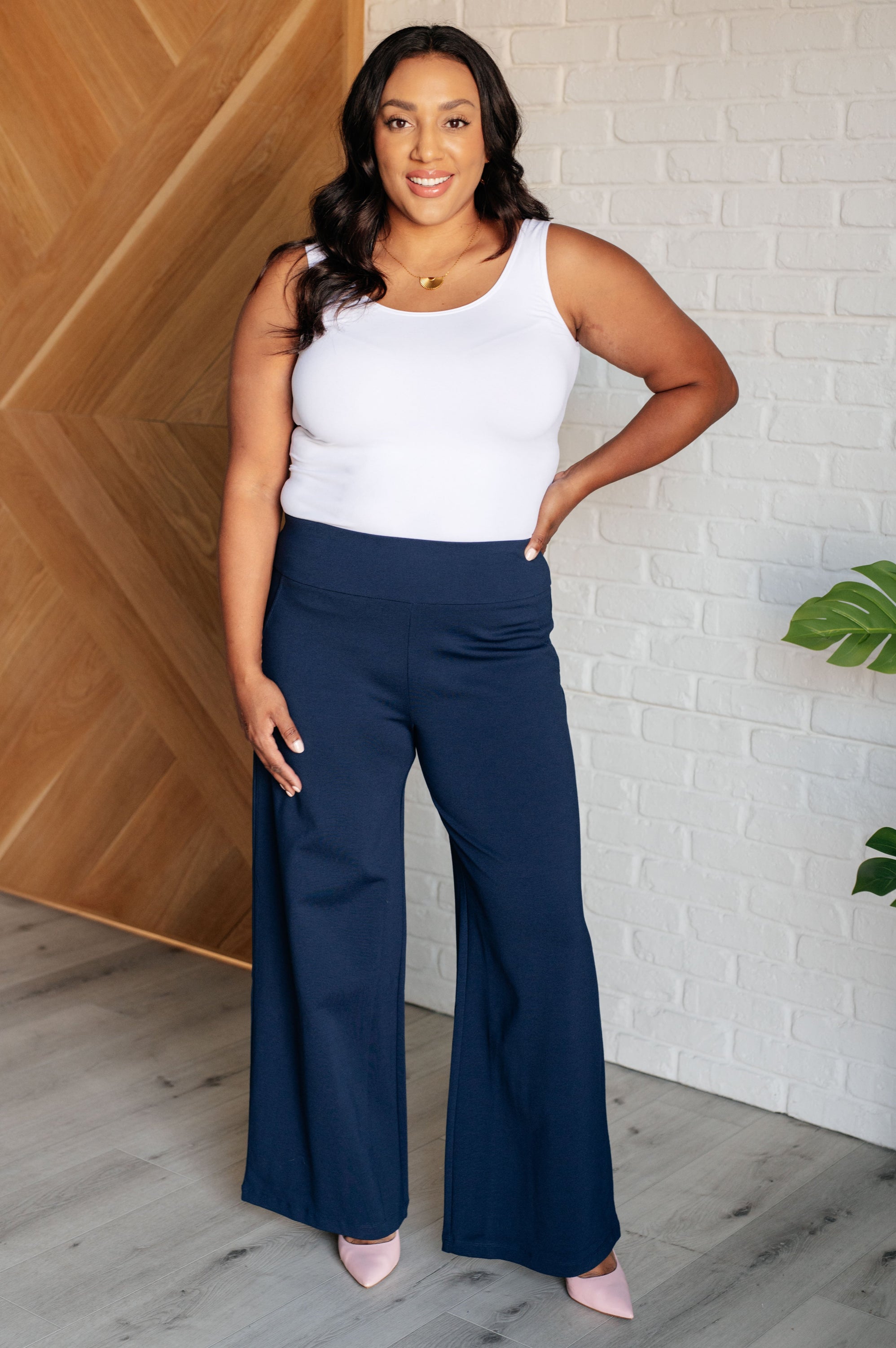 A pair of navy Magic Wide Leg Pants made from high stretch ponte knit fabric, featuring a wide leg design and faux welt pocket.