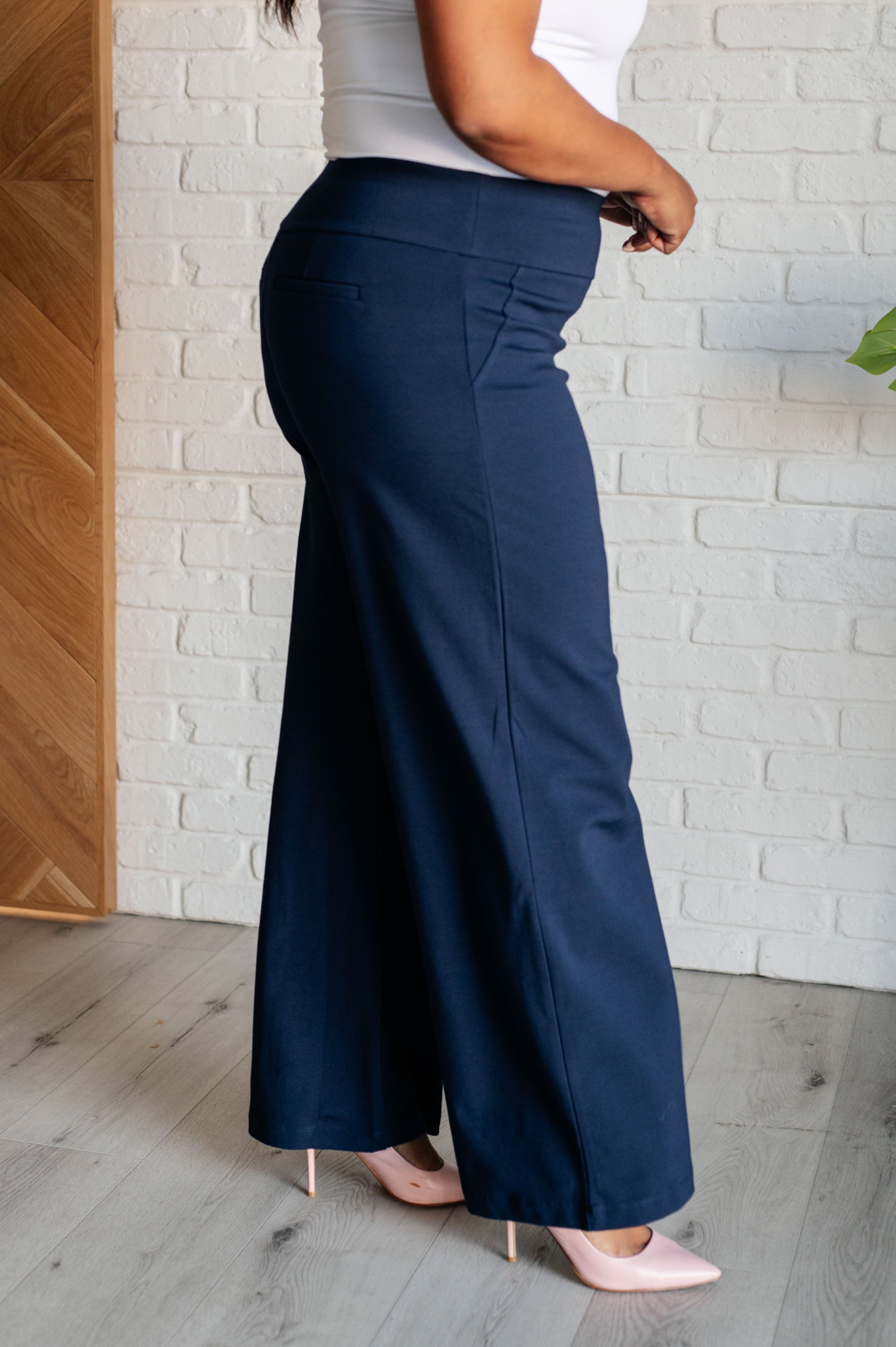 A pair of navy Magic Wide Leg Pants made from high stretch ponte knit fabric, featuring a wide leg design and faux welt pocket.