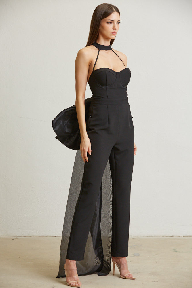 Majesty Bow Back Jumpsuit featuring a large bow trim at the back, mock neck, and tapered leg fit, made from solid woven fabric with organza trim.