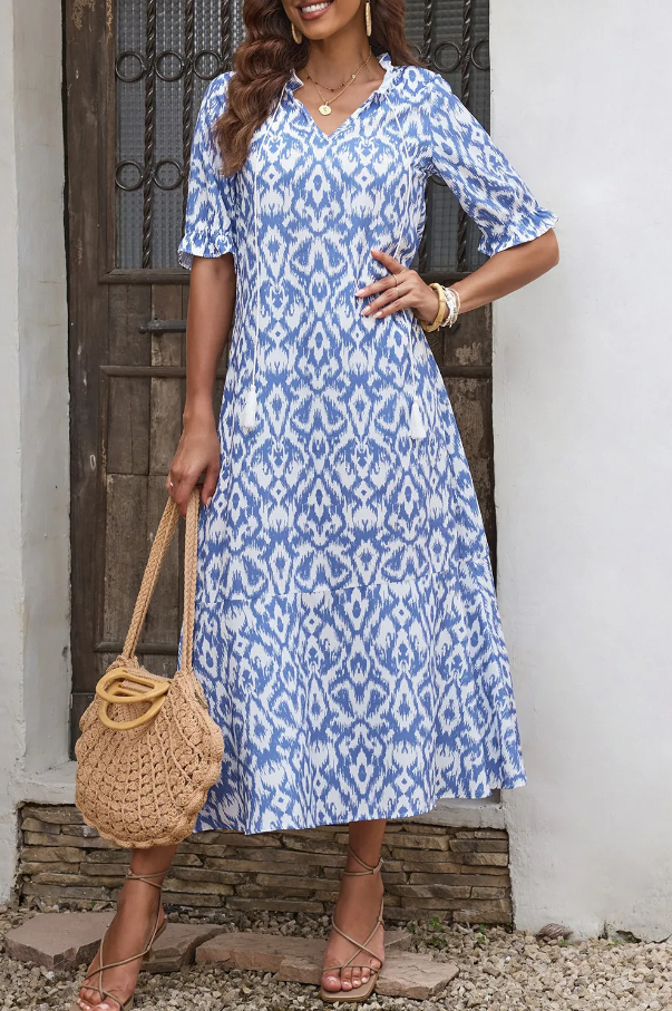 Light blue maxi dress with geometric print, featuring a V-neckline and ruffled short sleeves, ankle-length skirt.