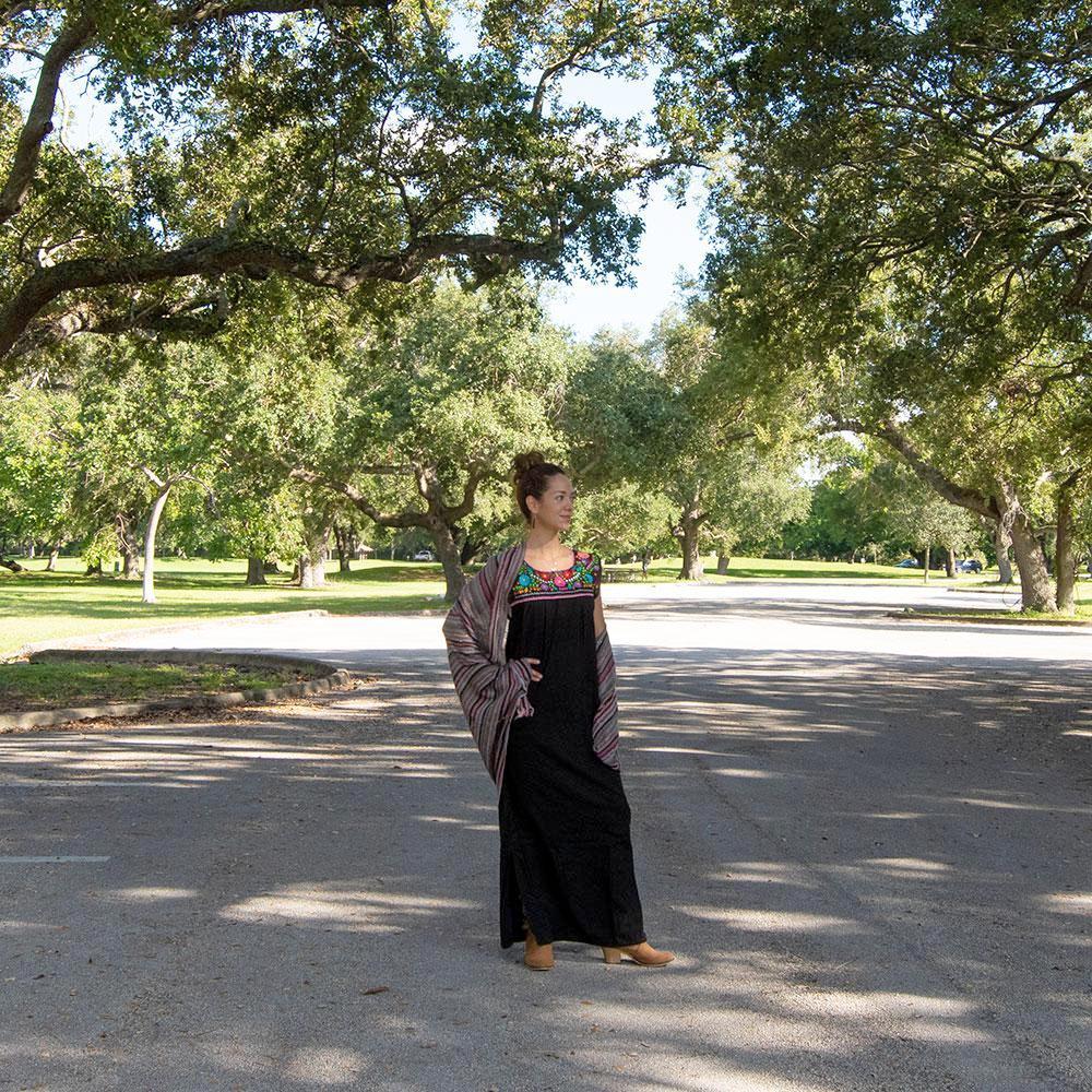 Maxi Isidra black dress featuring colorful hand-embroidered flowers, showcasing intricate craftsmanship and bohemian style.