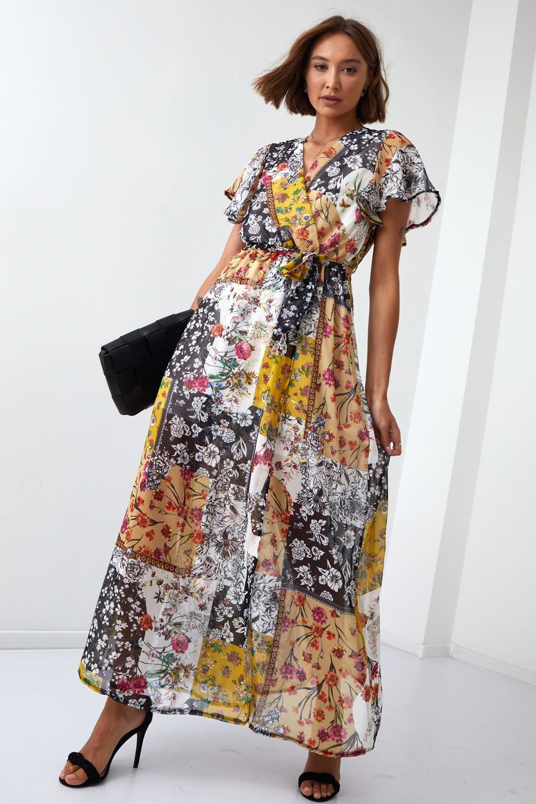 A vibrant yellow maxi wrap dress with floral print, featuring butterfly sleeves and a matching belt, displayed elegantly on a mannequin.