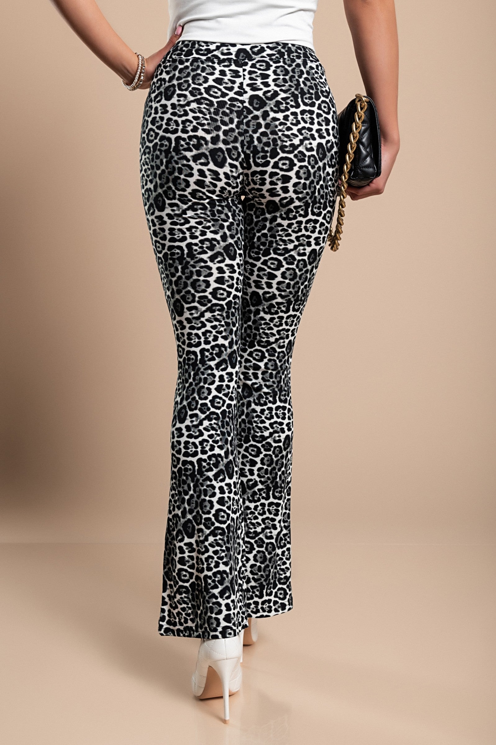 Modne hlače na zvon z leopardjim potiskom, črne barve, prikazane na belem ozadju.