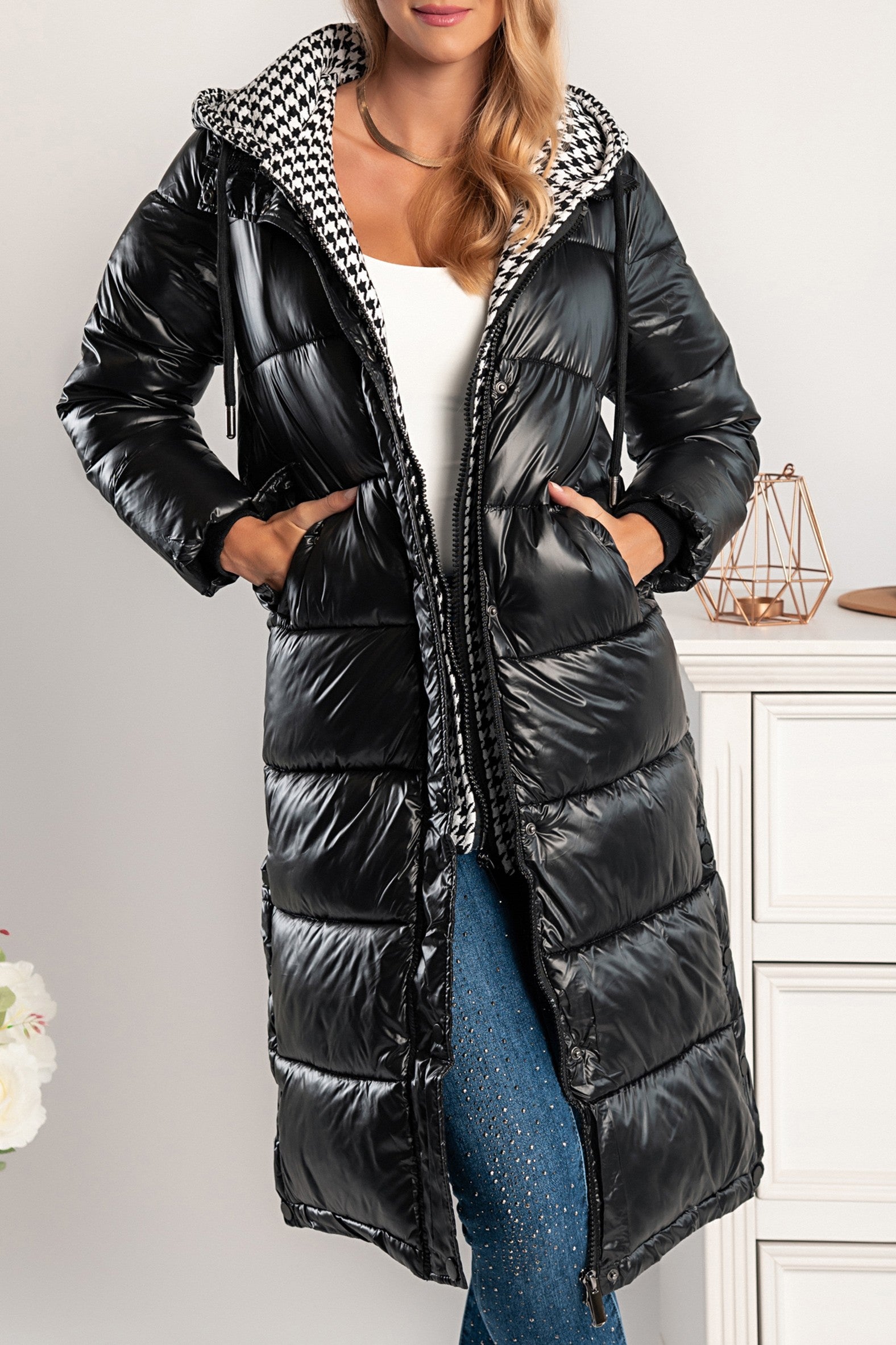 Moena long quilted black jacket with detachable hood and pepita pattern, featuring two front pockets and double zipper fastening.