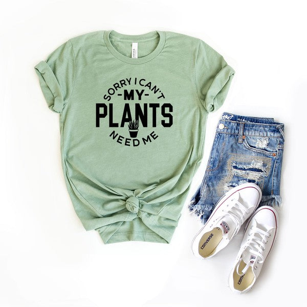 My Plants Need Me Short Sleeve Graphic Tee in various colors, showcasing a playful plant-themed graphic.