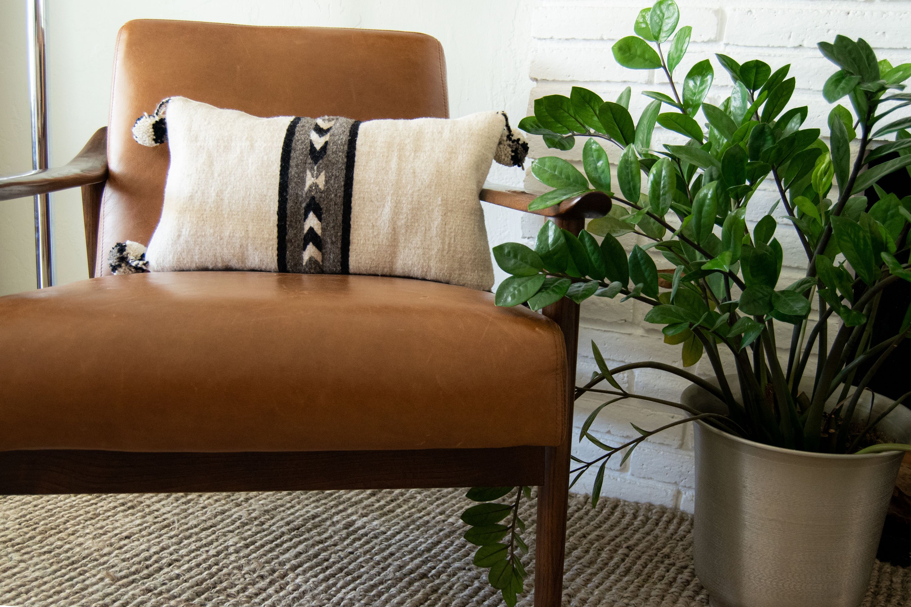 Neza Native Arrows black and white lumbar pillow cover with geometric designs and pompons on corners, showcasing artisan craftsmanship.