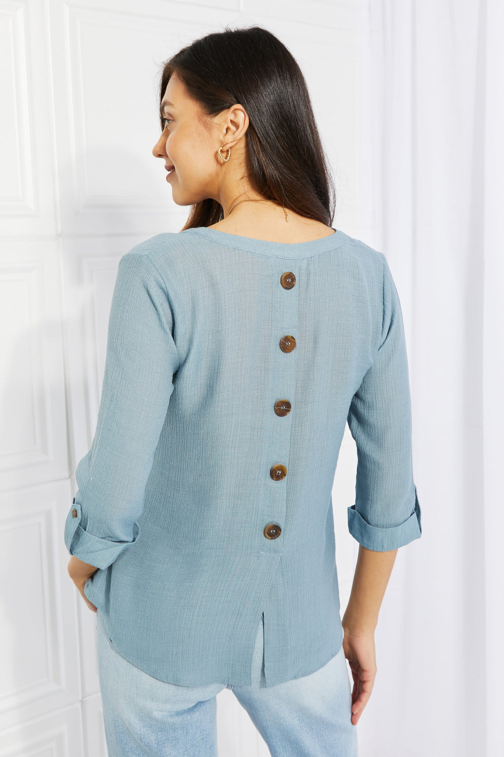 Light teal notched blouse with decorative buttons and half sleeves, styled casually.