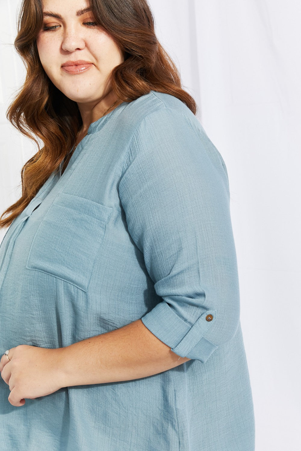 Light teal notched blouse with decorative buttons and half sleeves, styled casually.