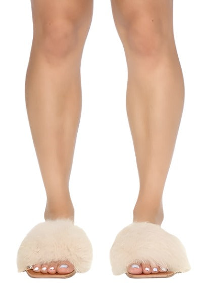 A pair of nude square toe slide sandals with a faux fur upper, showcasing a stylish and comfortable design.