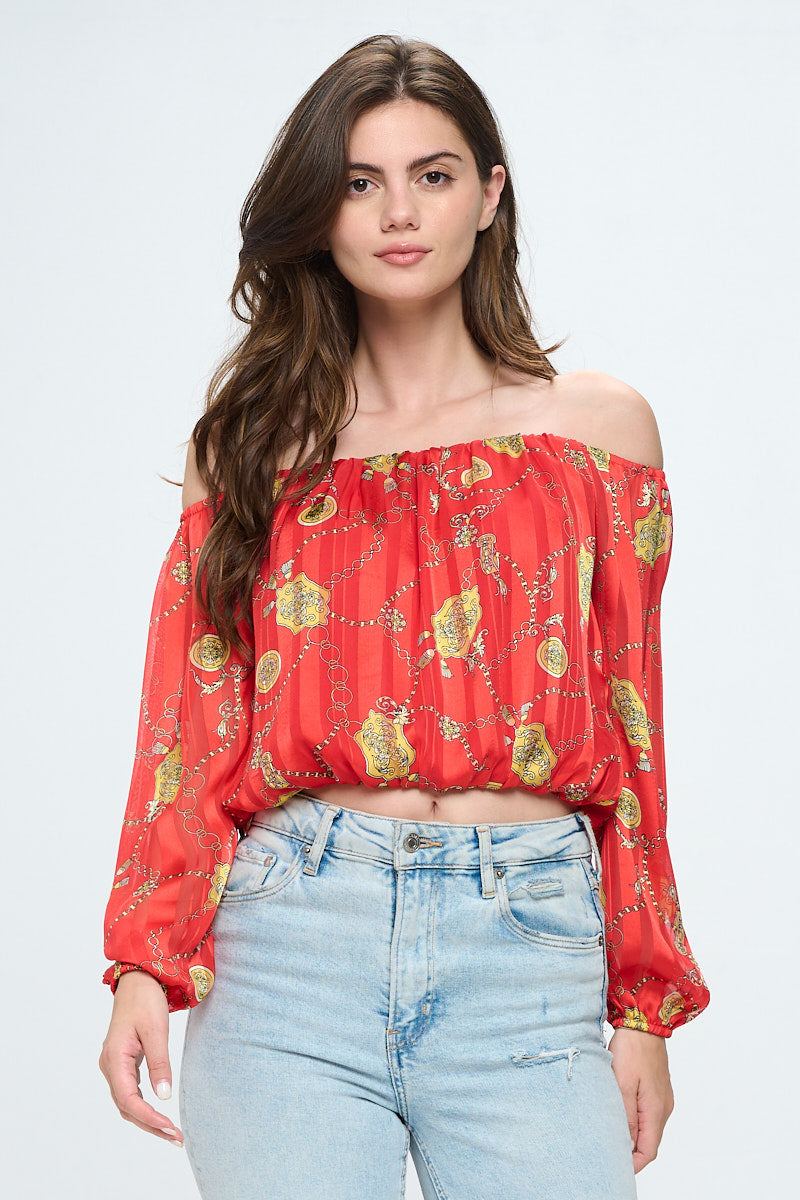 Off-shoulder long-sleeve crop top in red chiffon with gold chain print, featuring elastic wrist detail.