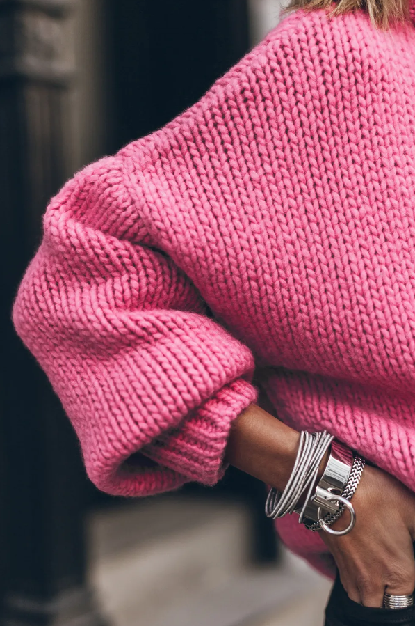 Ohlapen roza pulover z visokim ovratnikom in dolgimi rokavi, idealen za udobno nošenje.