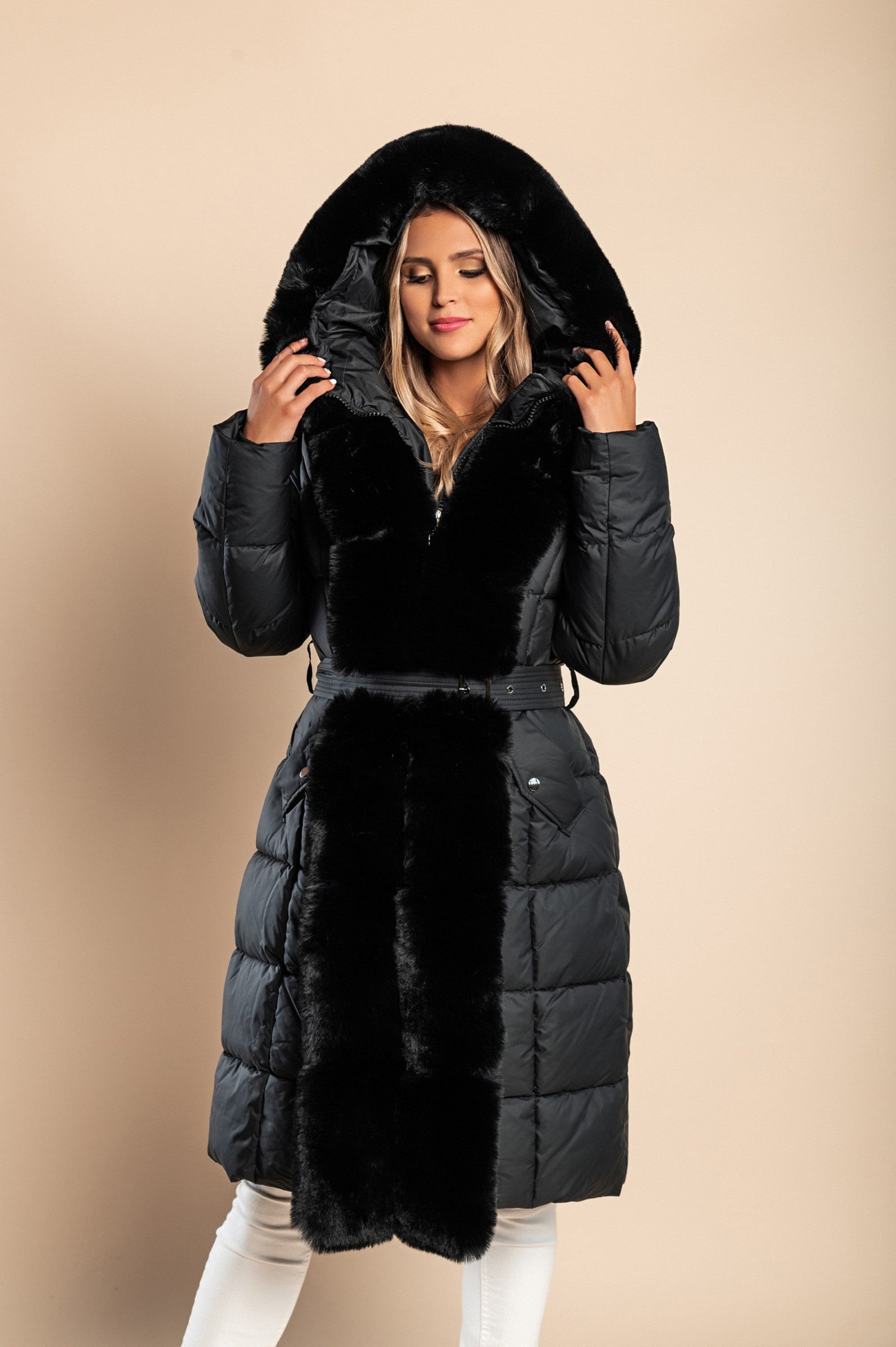 Padded winter jacket in black with removable faux fur hood and decorative belt, featuring side pockets and long sleeves.