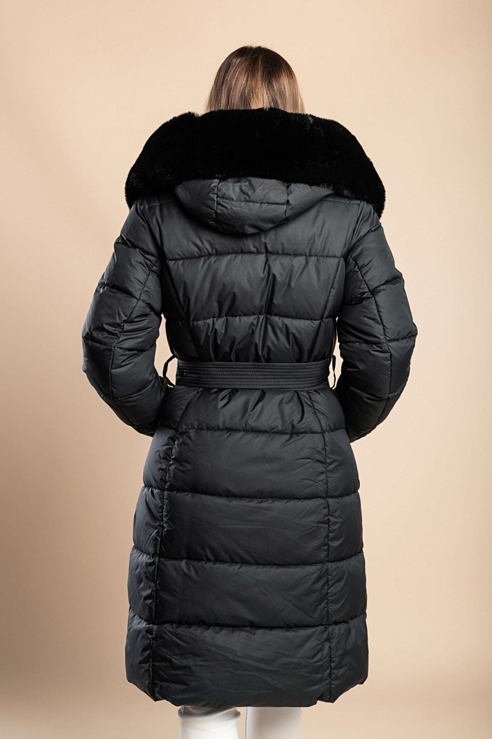 Padded winter jacket in black with removable faux fur hood and decorative belt, featuring side pockets and long sleeves.
