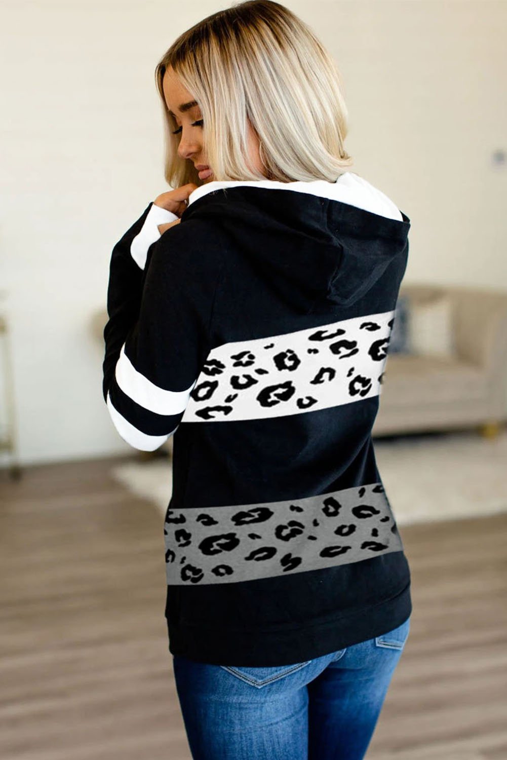 A stylish black hoodie featuring leopard print accents, inclined zipper, and thumb holes, perfect for casual wear.