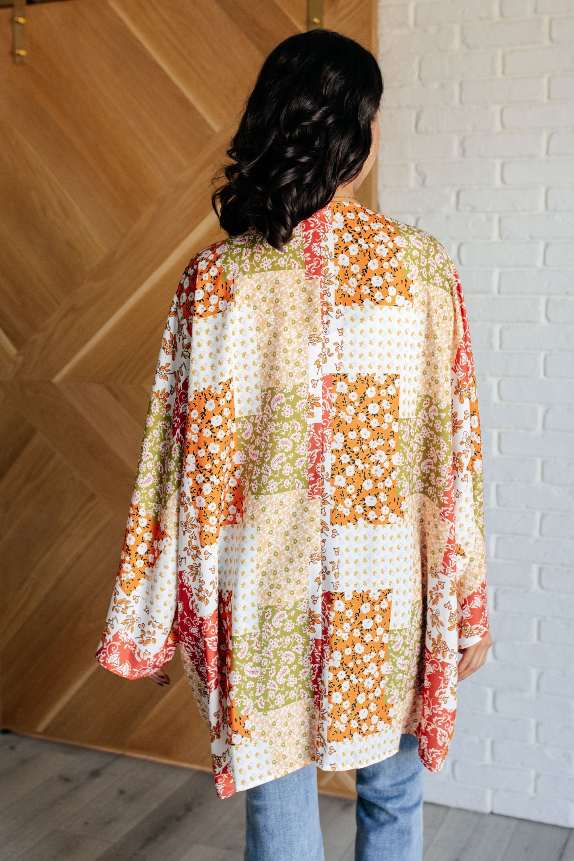 A vibrant mixed floral kimono with dolman sleeves and an open front, made from lightweight poplin fabric.