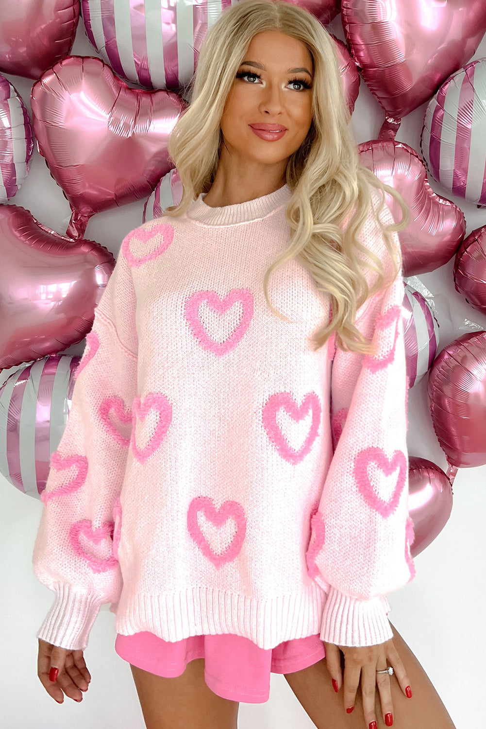 A stylish pink sweater featuring heart shapes and bubble sleeves, perfect for casual wear.