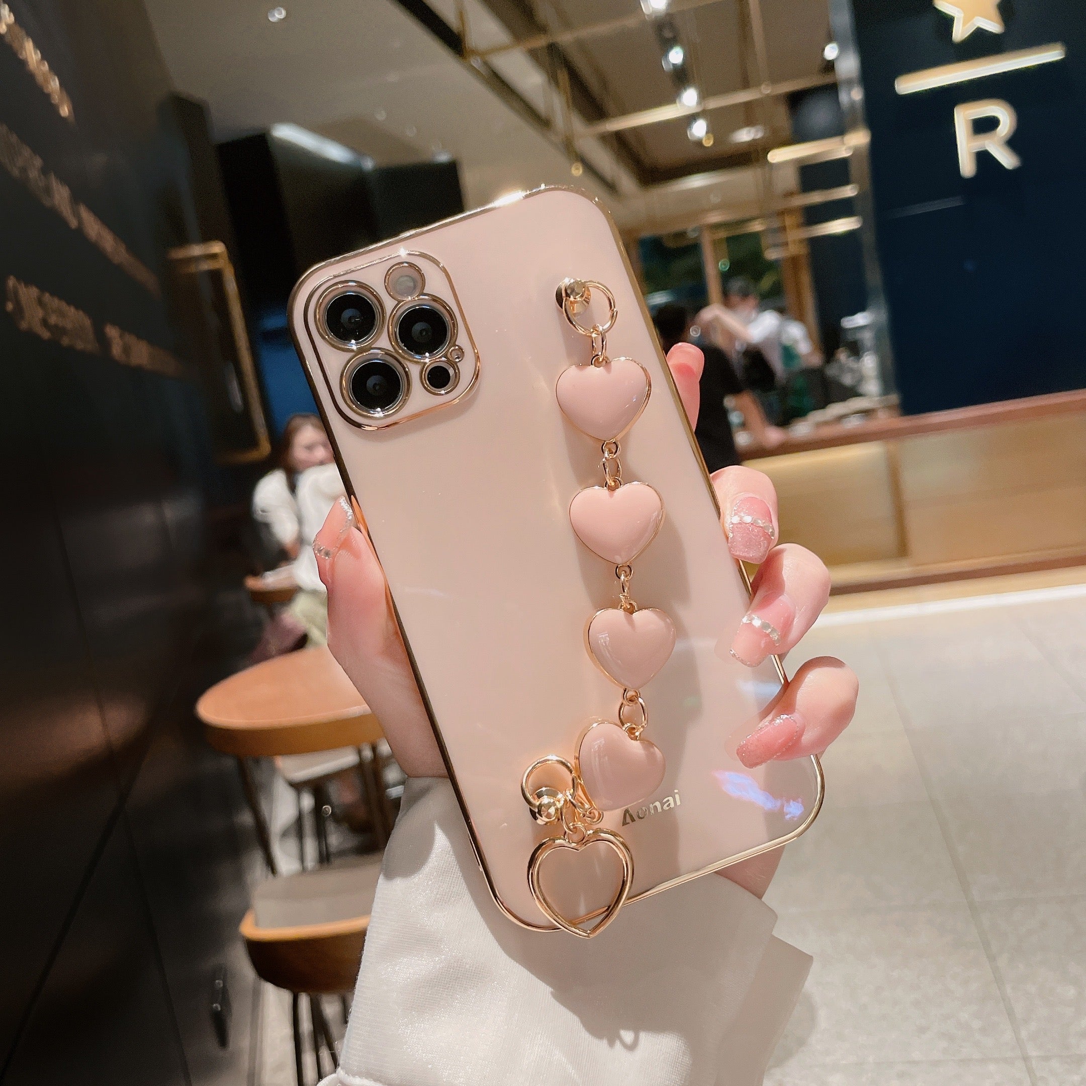 A stylish pink phone case with a heart wristband, designed for most phone models, featuring a glossy finish and durable material.