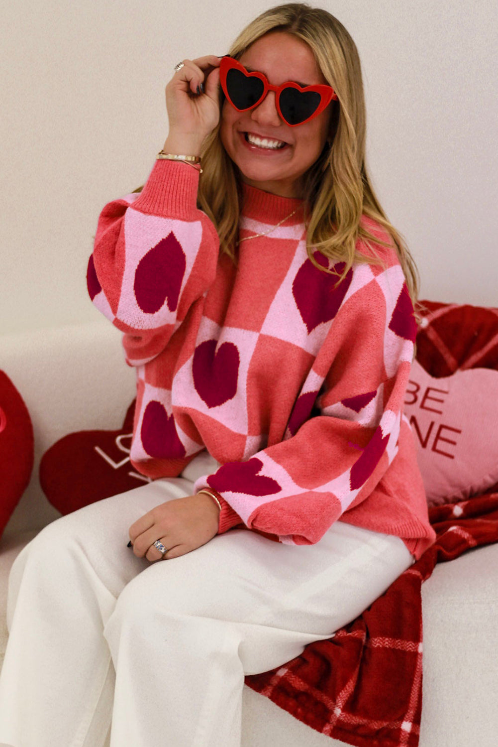 A stylish pink plus size sweater featuring a love heart block pattern, mock neck, and lantern sleeves, perfect for Valentine's Day.
