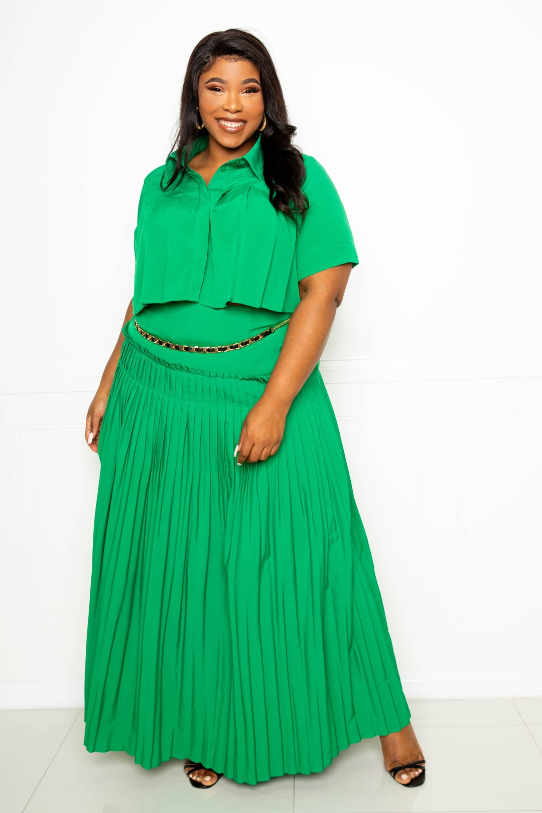 A stylish pleated cropped shirt paired with a flowing maxi skirt in vibrant green, showcasing a chic and elegant outfit for plus sizes.