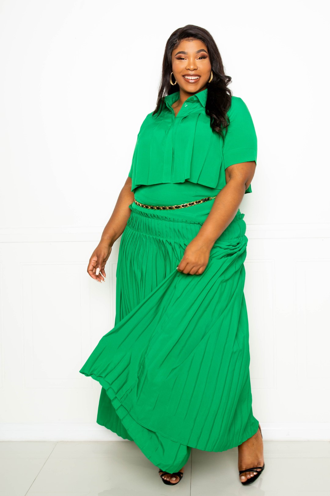 A stylish pleated cropped shirt paired with a flowing maxi skirt in vibrant green, showcasing a chic and elegant outfit for plus sizes.