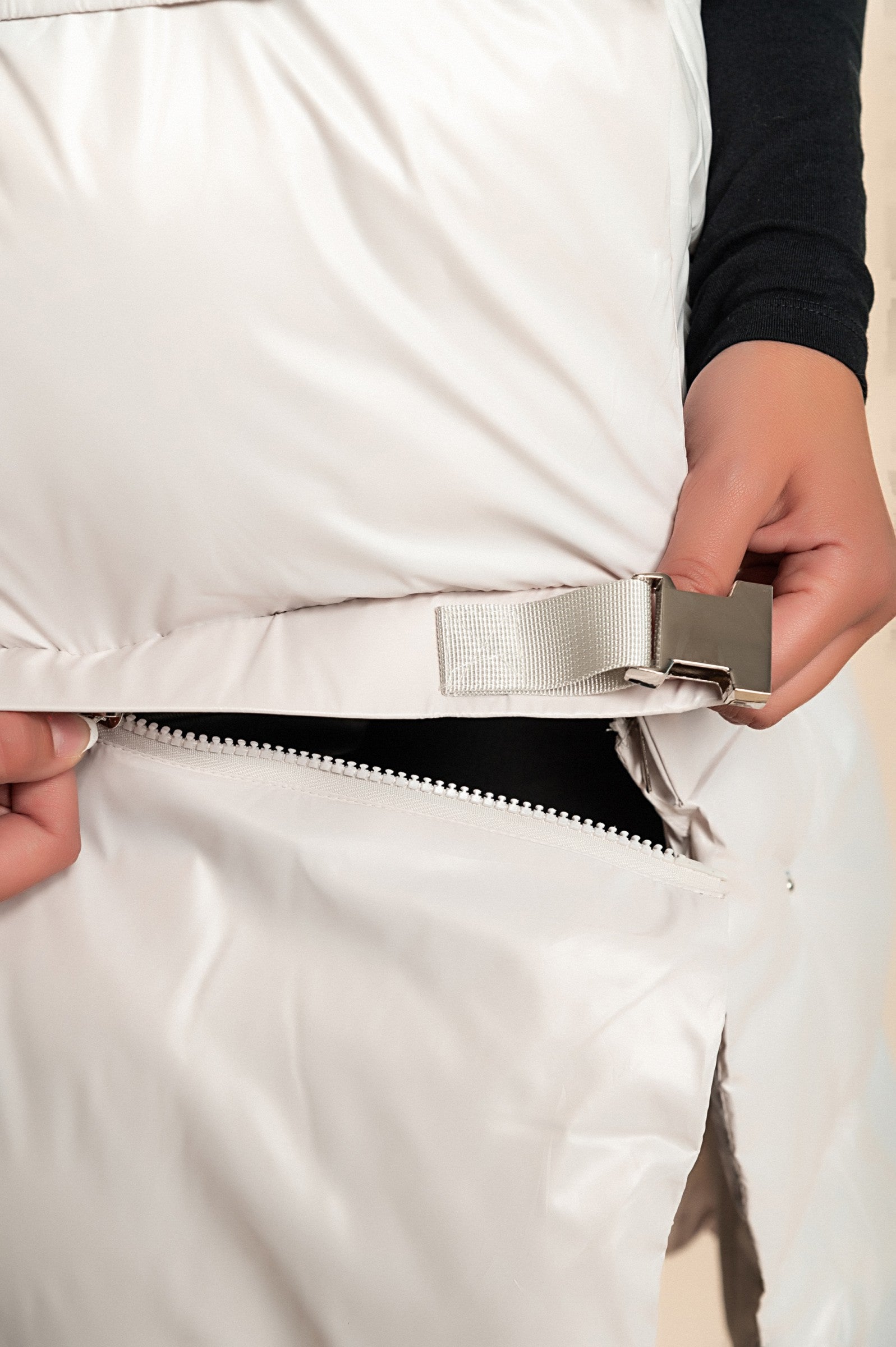 Prešit brezrokavnik Sines v bež barvi z visokim ovratnikom in gumbi na pritisk, prikazan v elegantnem okolju.