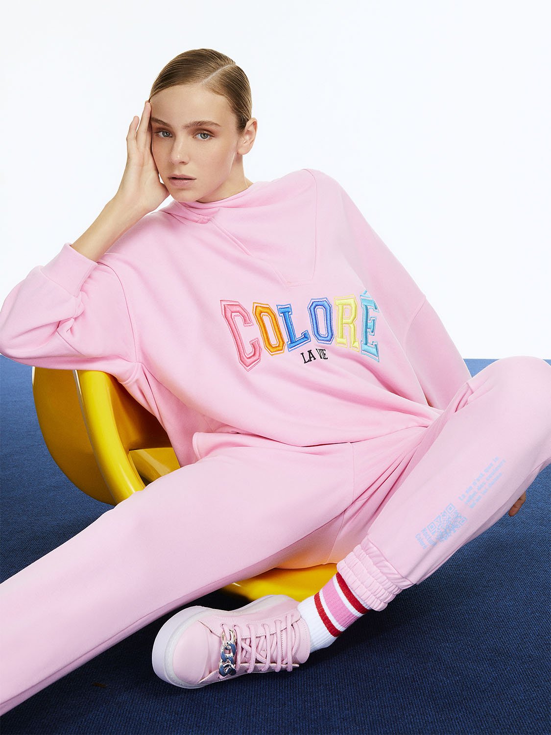 A pair of high-waisted ankle-length printed jogging pants featuring an elastic waistband and vibrant colors of orange, pink, and blue.