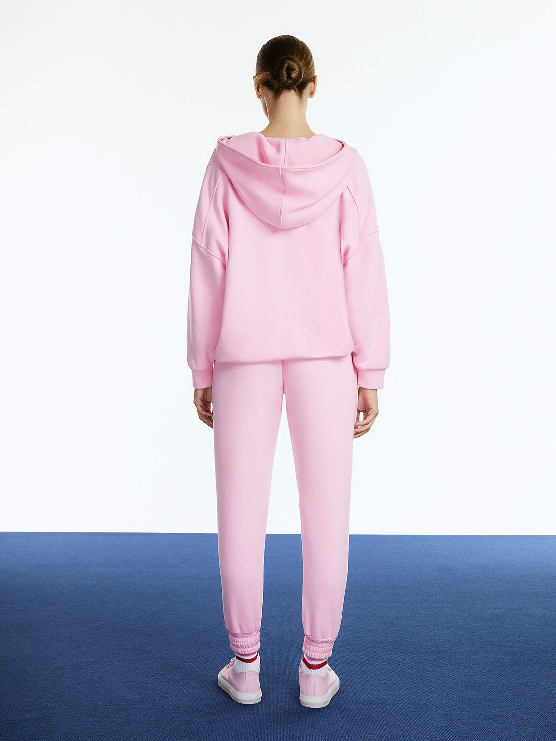 A pair of high-waisted ankle-length printed jogging pants featuring an elastic waistband and vibrant colors of orange, pink, and blue.