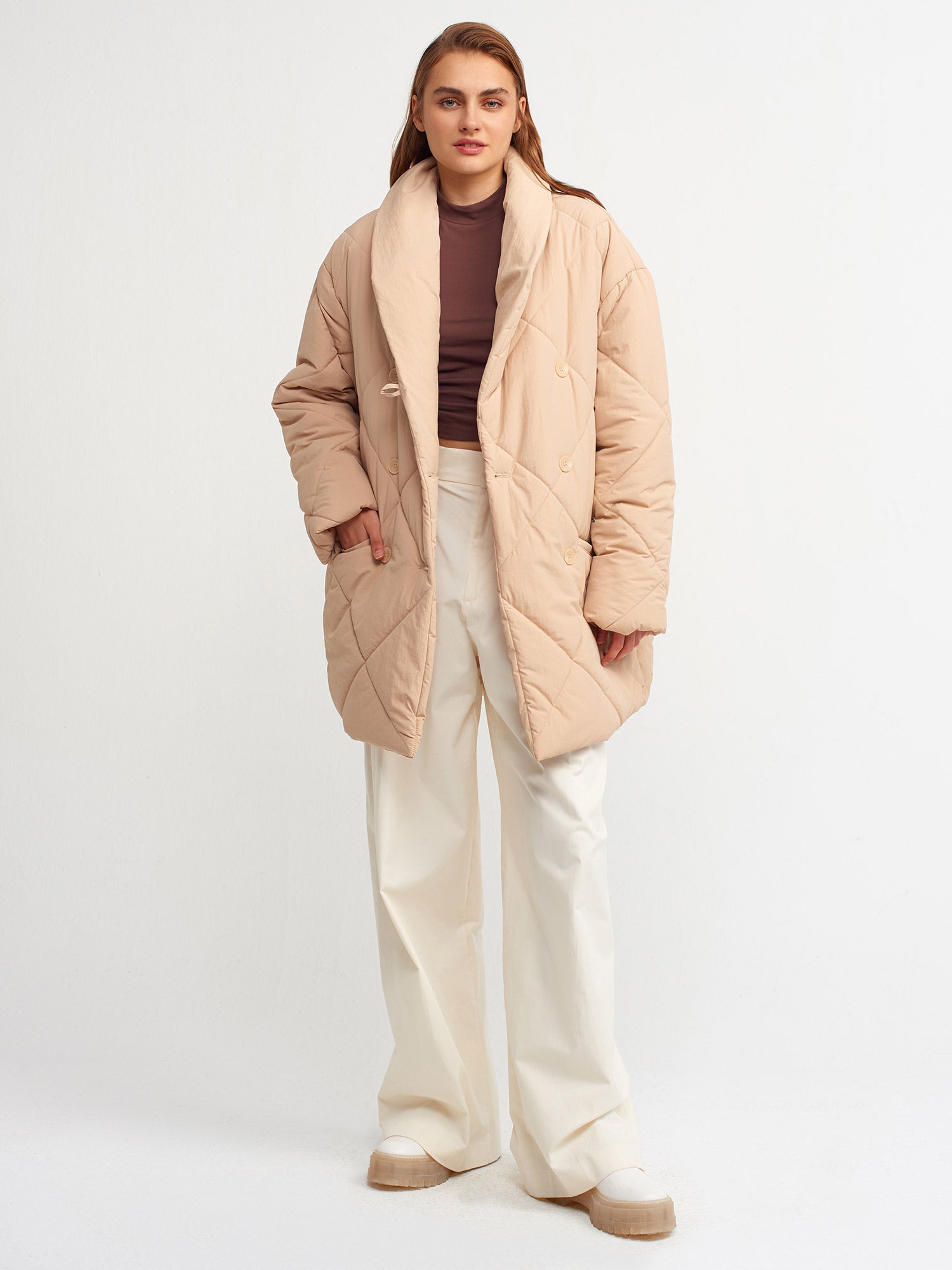 A stylish quilted coat made from 100% nylon, featuring a sleek design and warm insulation, perfect for cold weather.