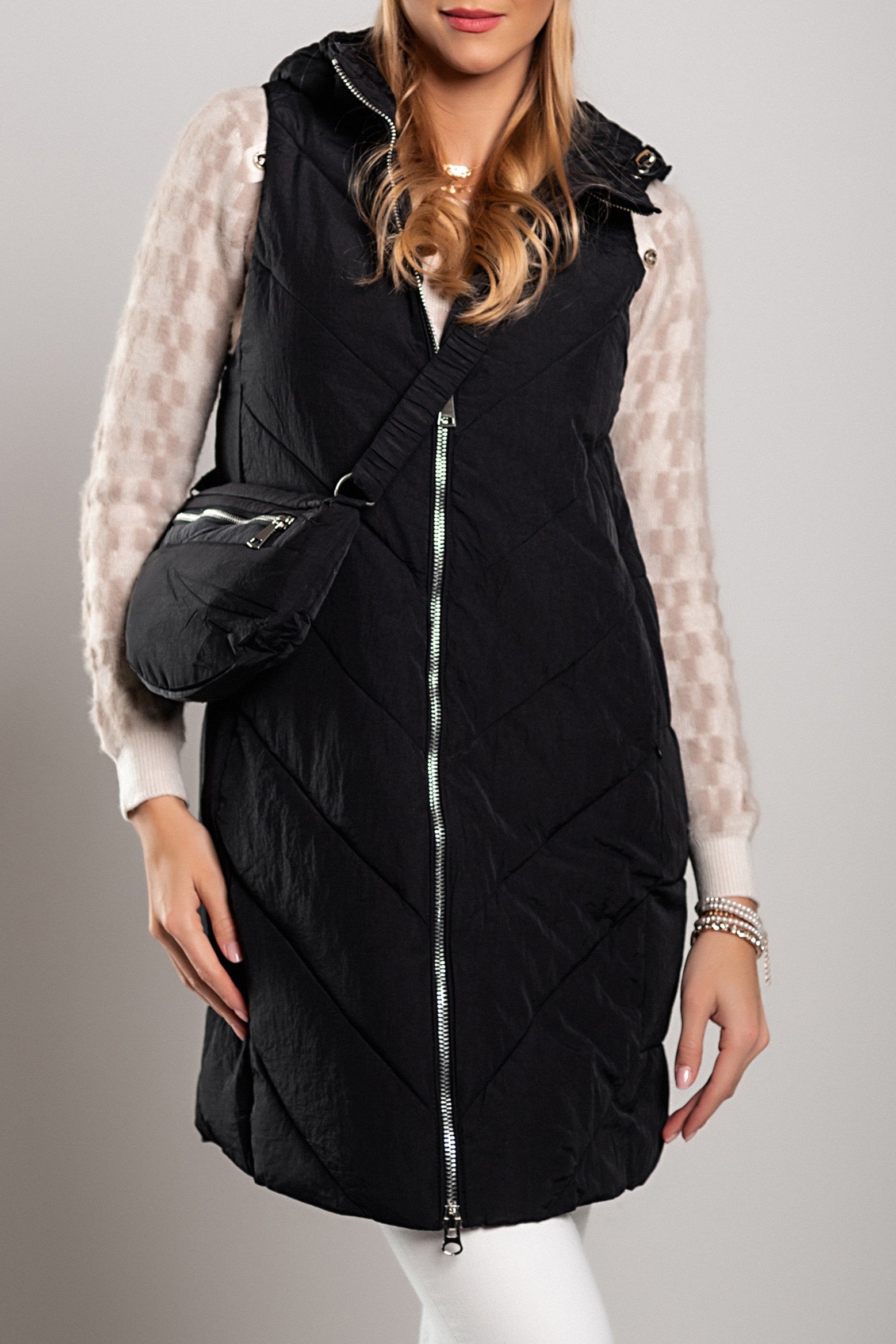 Black quilted gilet with attached bag, featuring a full zip closure and hood, designed for warmth and style.