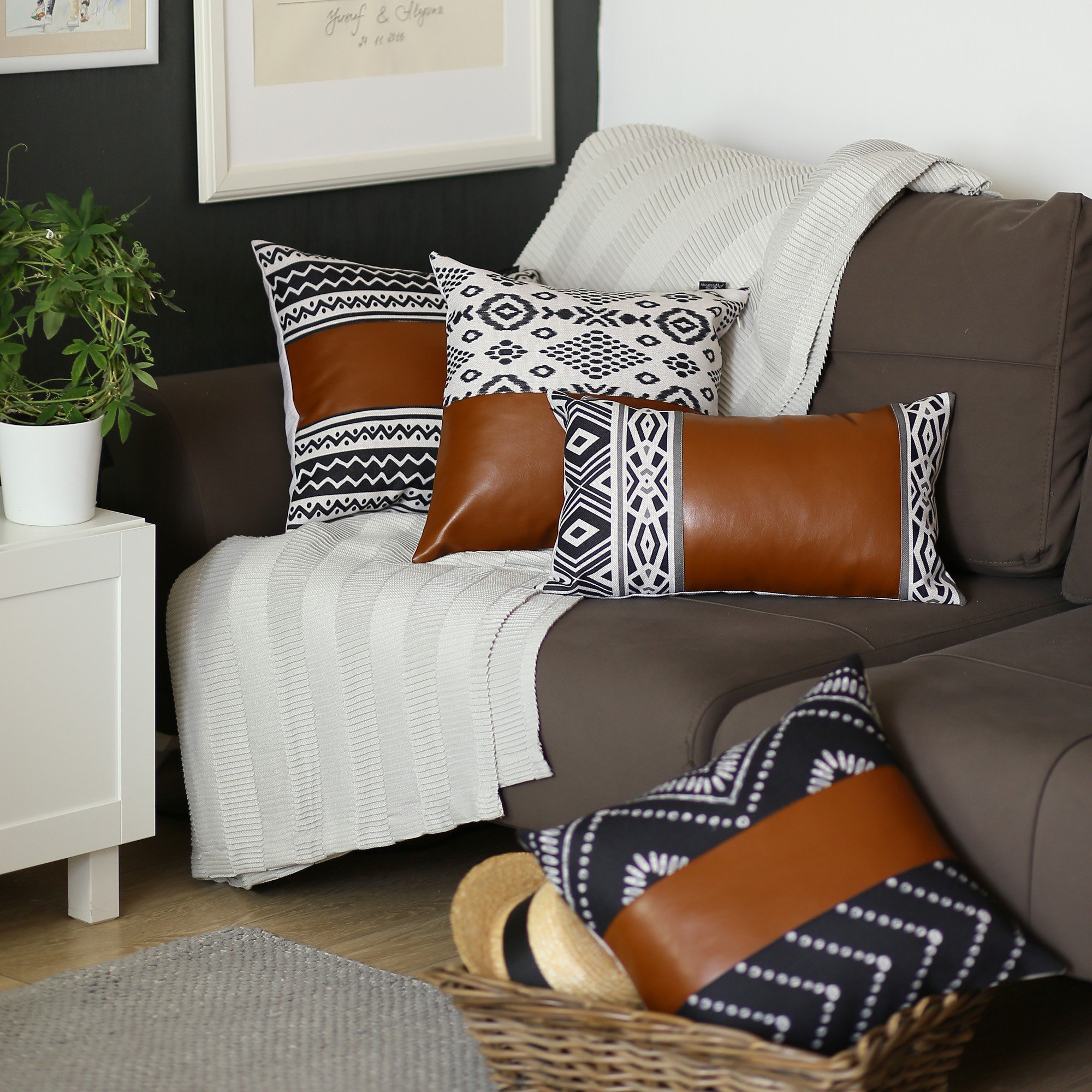 Rectangular lumbar pillow cover in rustic brown faux leather with geometric patterns in charcoal black and daisy white, featuring a hidden zipper.