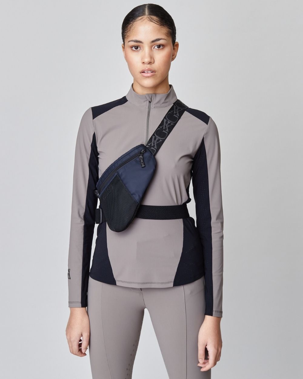 A sleek black riding bag made from recycled nylon, featuring adjustable straps and multiple pockets for secure storage.