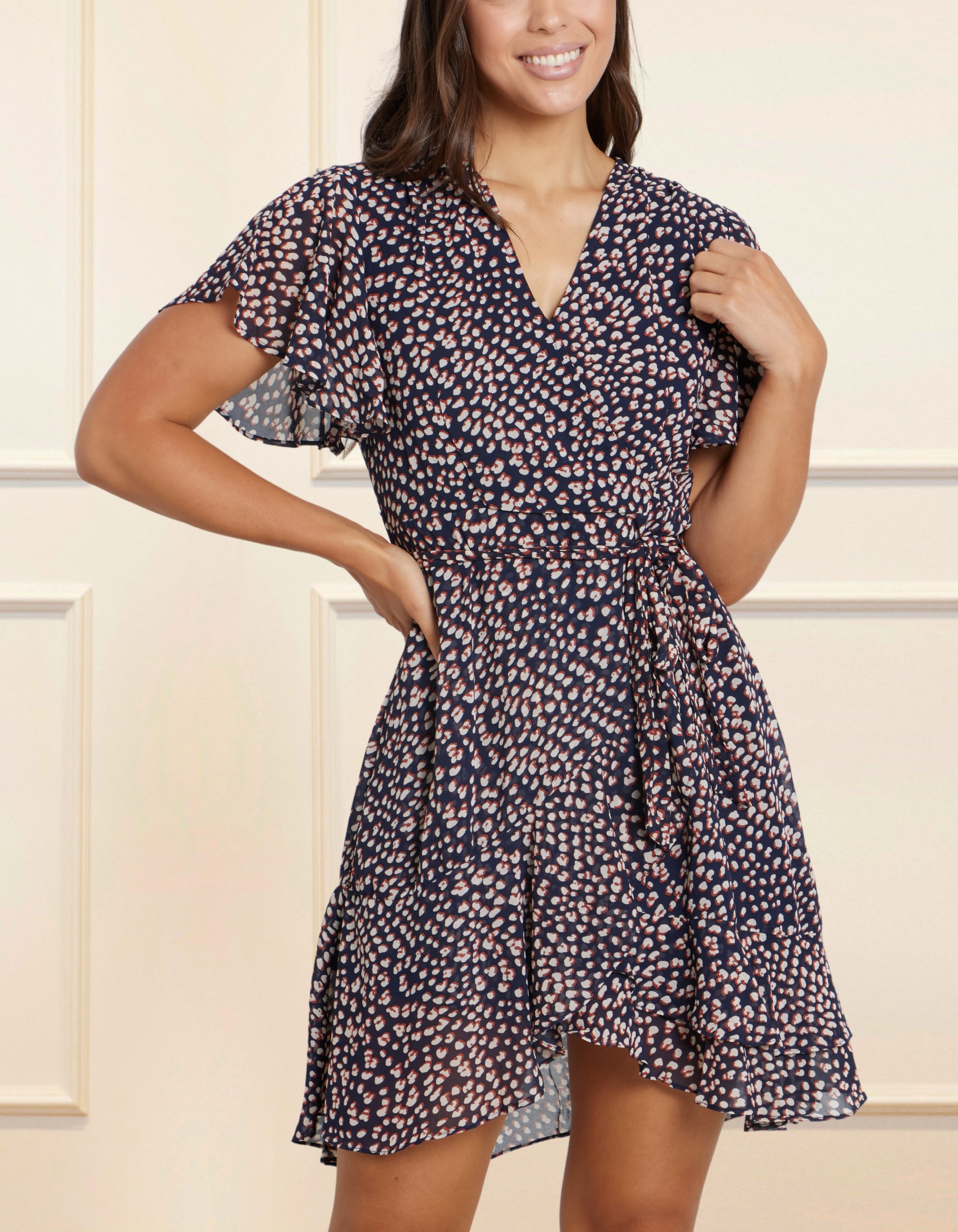 Romane Dress Cross-Over Wrap in navy with flutter sleeves and a floral print, featuring a removable belt and flounce hemline.