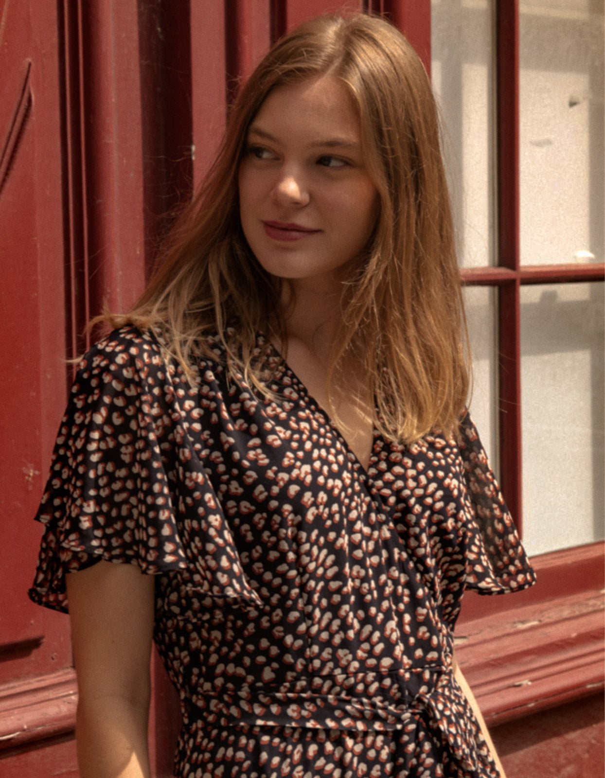 Romane Dress Cross-Over Wrap in navy with flutter sleeves and a floral print, featuring a removable belt and flounce hemline.