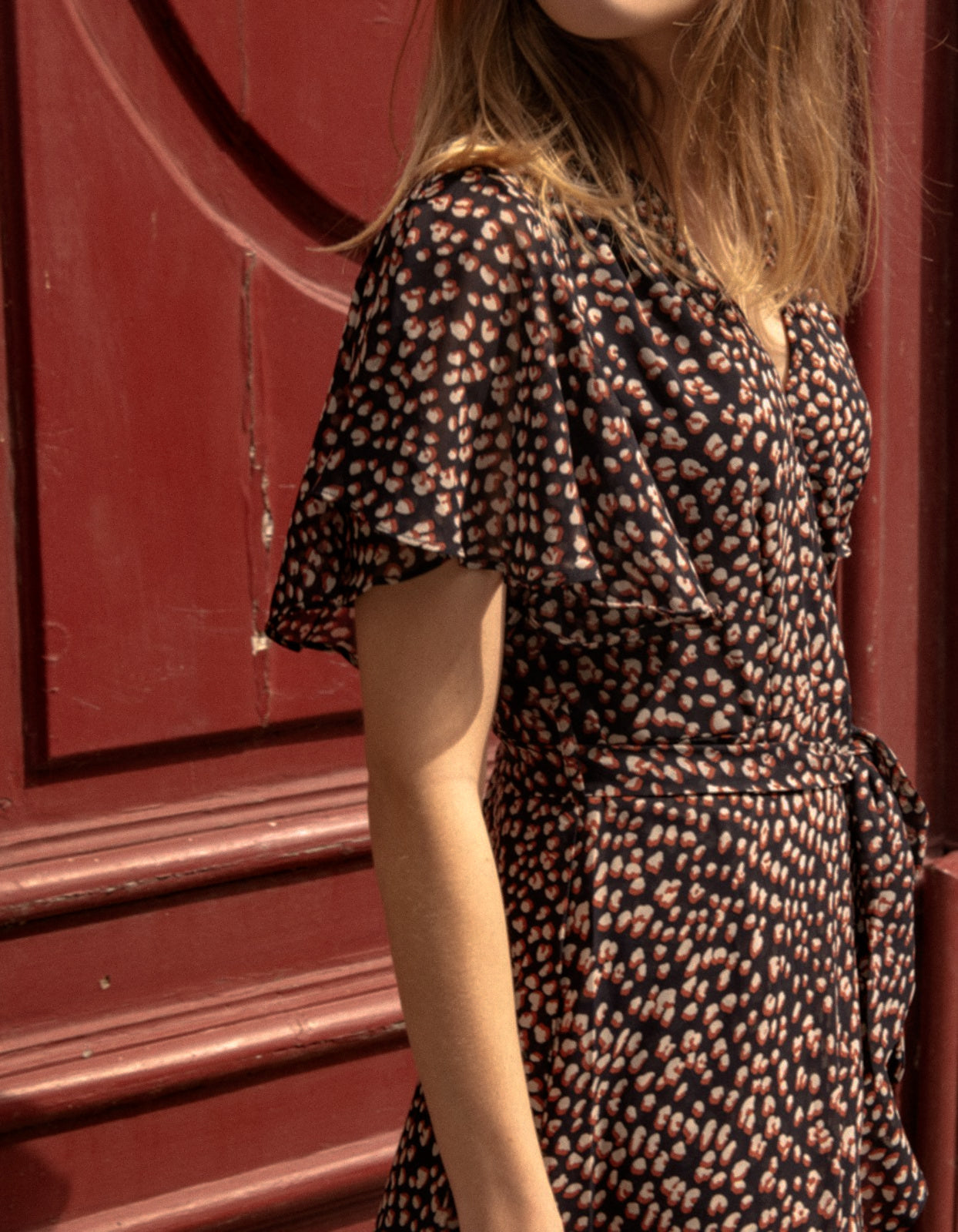 Romane Dress Cross-Over Wrap in navy with flutter sleeves and a floral print, featuring a removable belt and flounce hemline.