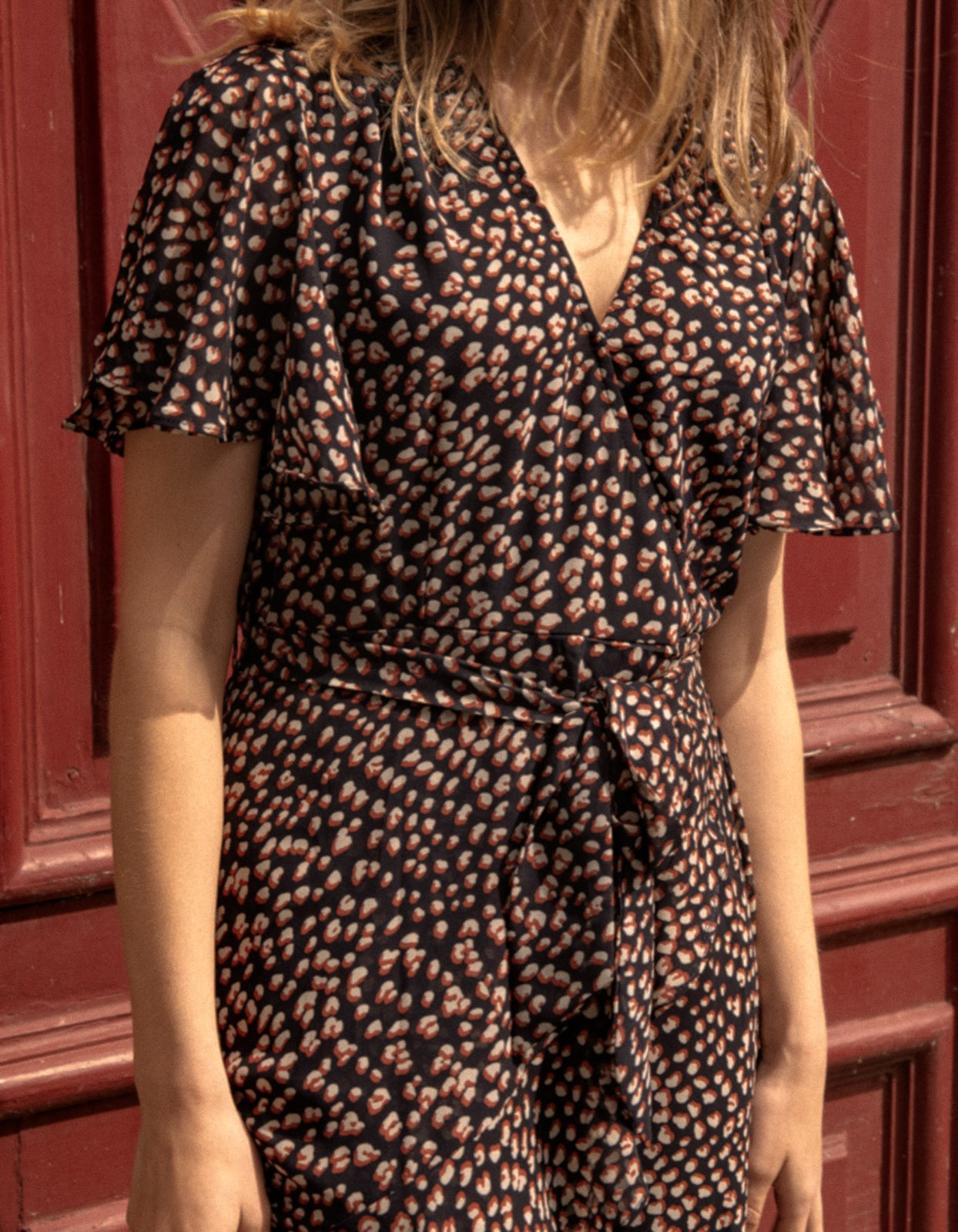 Romane Dress Cross-Over Wrap in navy with flutter sleeves and a floral print, featuring a removable belt and flounce hemline.