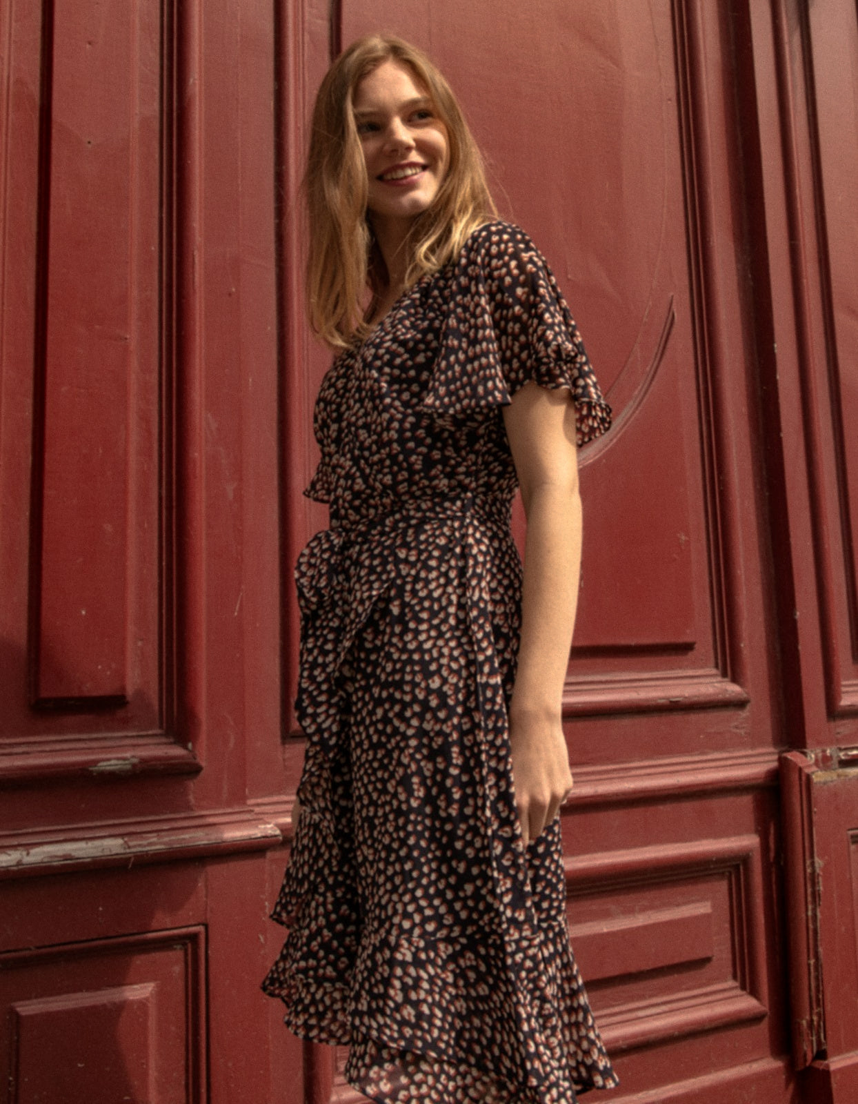 Romane Dress Cross-Over Wrap in navy with flutter sleeves and a floral print, featuring a removable belt and flounce hemline.