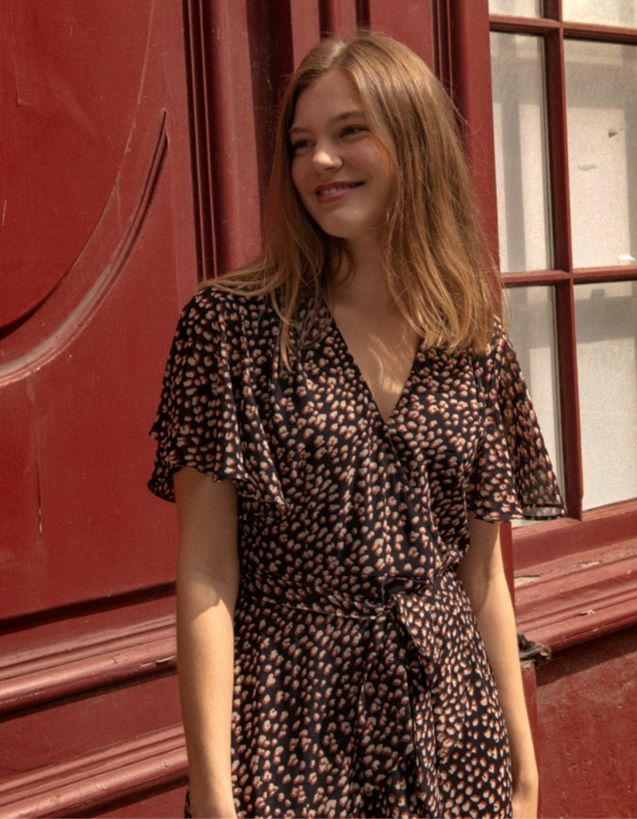 Romane Dress Cross-Over Wrap in navy with flutter sleeves and a floral print, featuring a removable belt and flounce hemline.