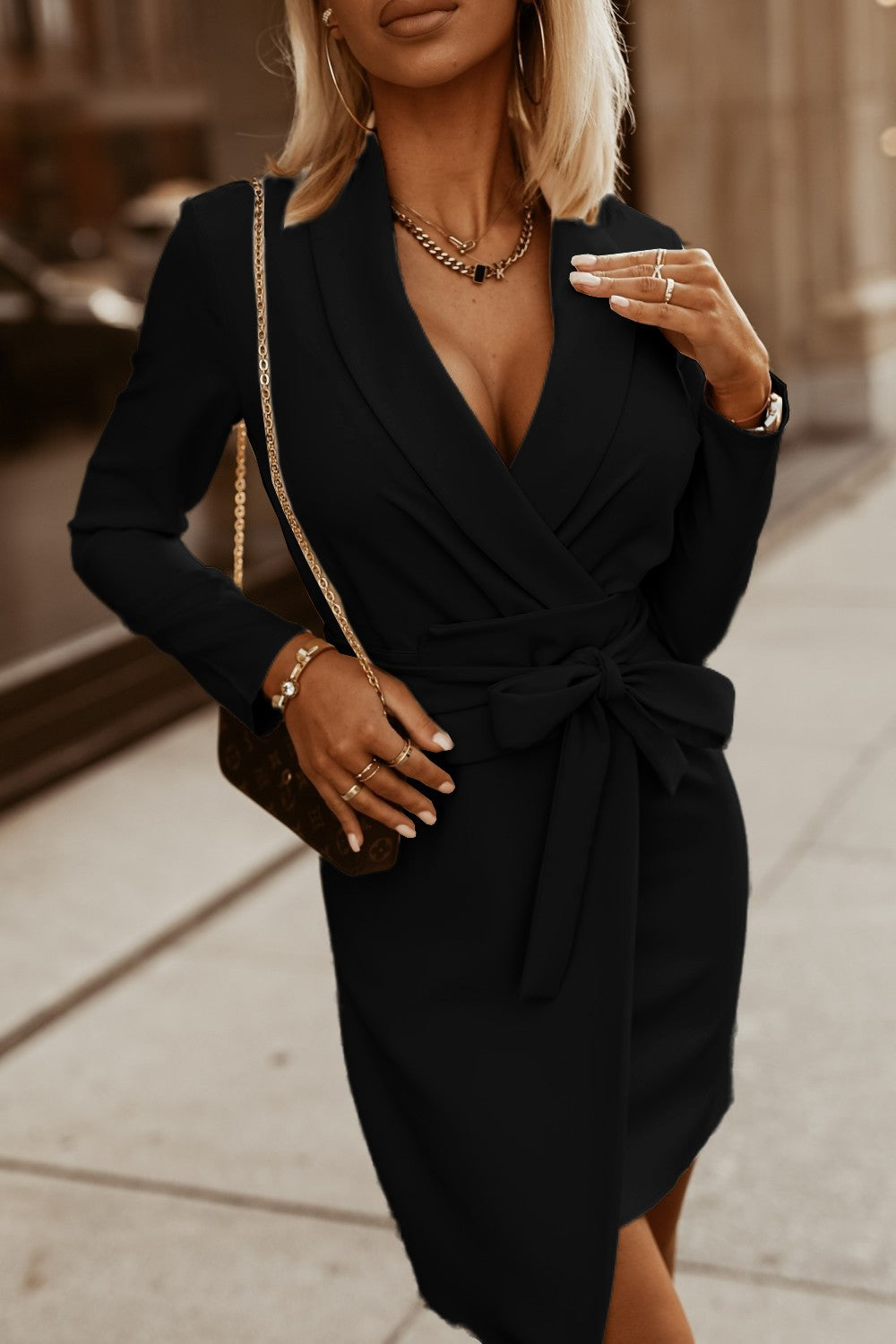 Ruby's elegant black wide-waisted mini dress featuring a deep neckline, long sleeves, and a mid-thigh skirt with a slit.