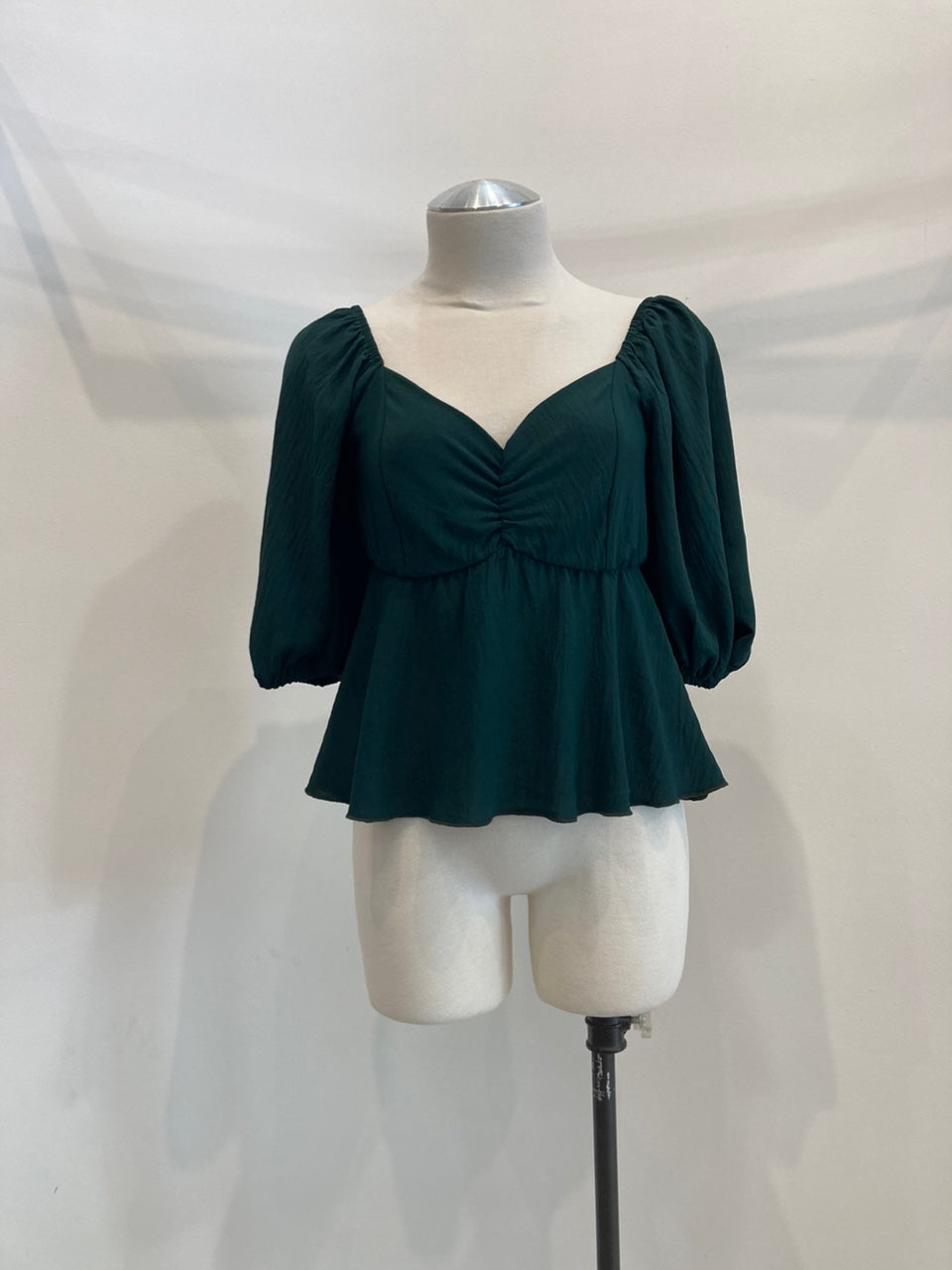 A stylish Ruched Peplum Blouse with balloon short sleeves and a V-neck, showcasing a flattering silhouette.