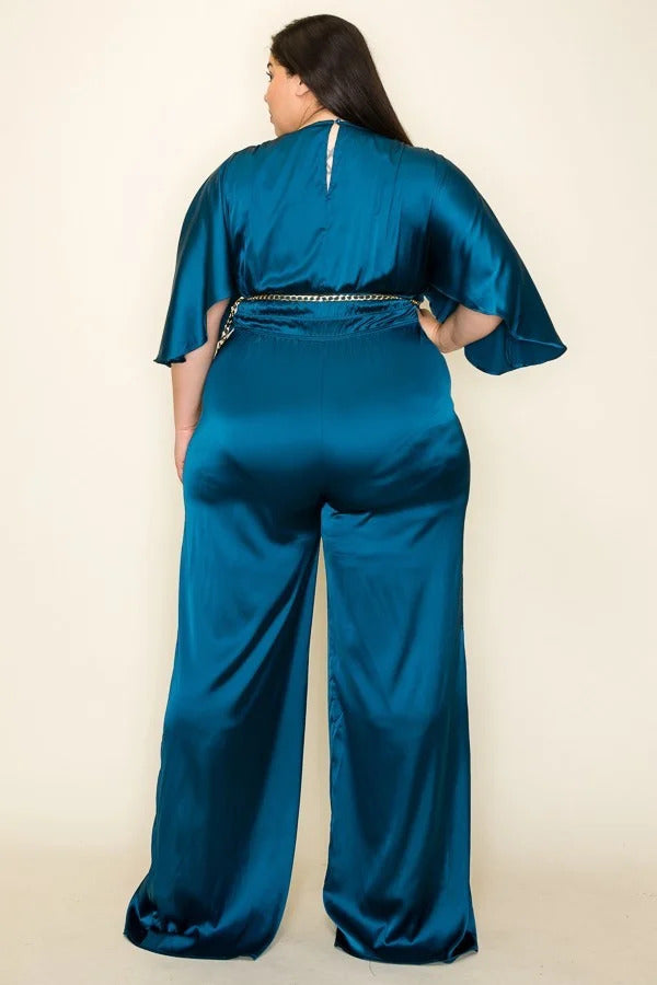 A teal satin jumpsuit featuring a wrap front, short sleeves, and a smocked waist, complemented by a stylish chain belt.