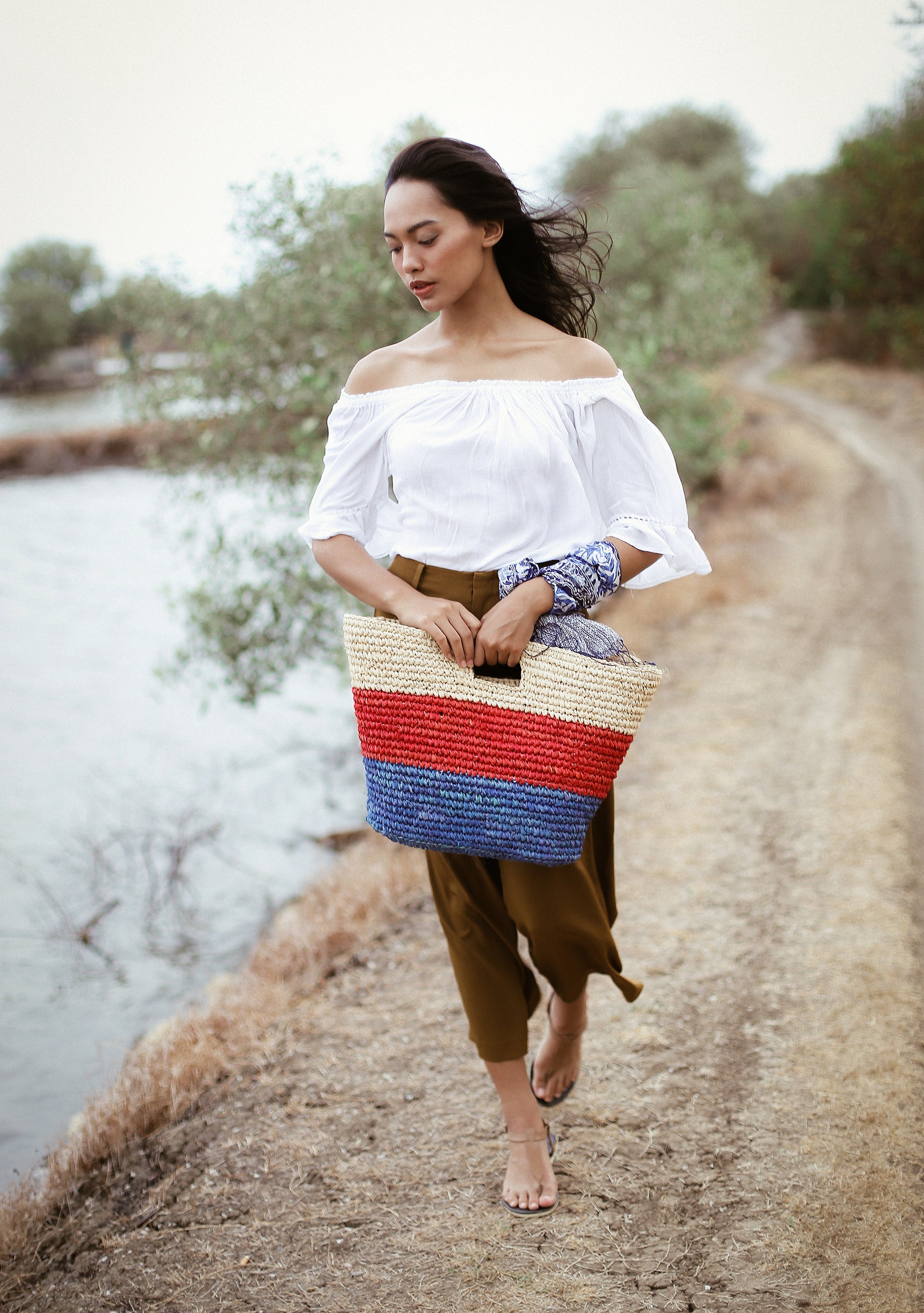 SAYAN Raffia Tote Bag in vibrant red and blue, handcrafted from natural raffia straws, perfect for beach outings.