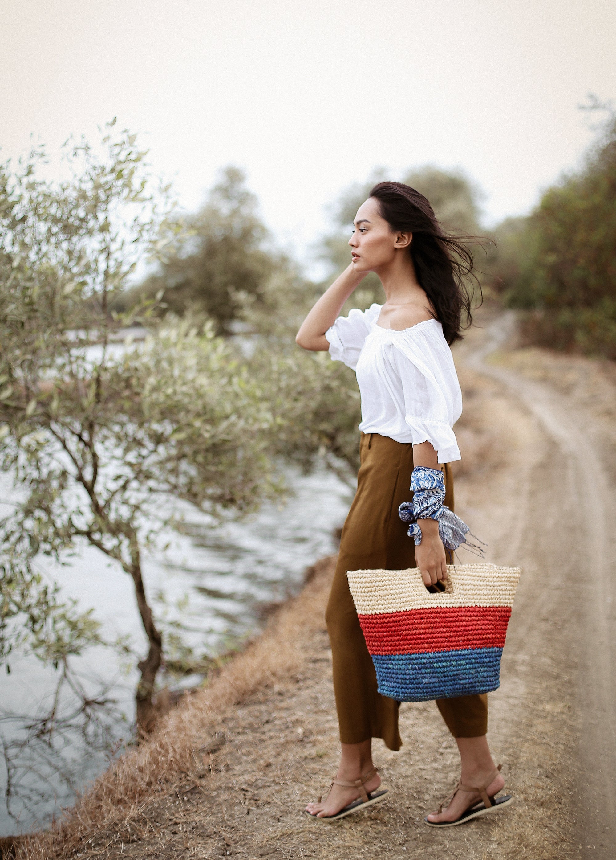 SAYAN Raffia Tote Bag in vibrant red and blue, handcrafted from natural raffia straws, perfect for beach outings.