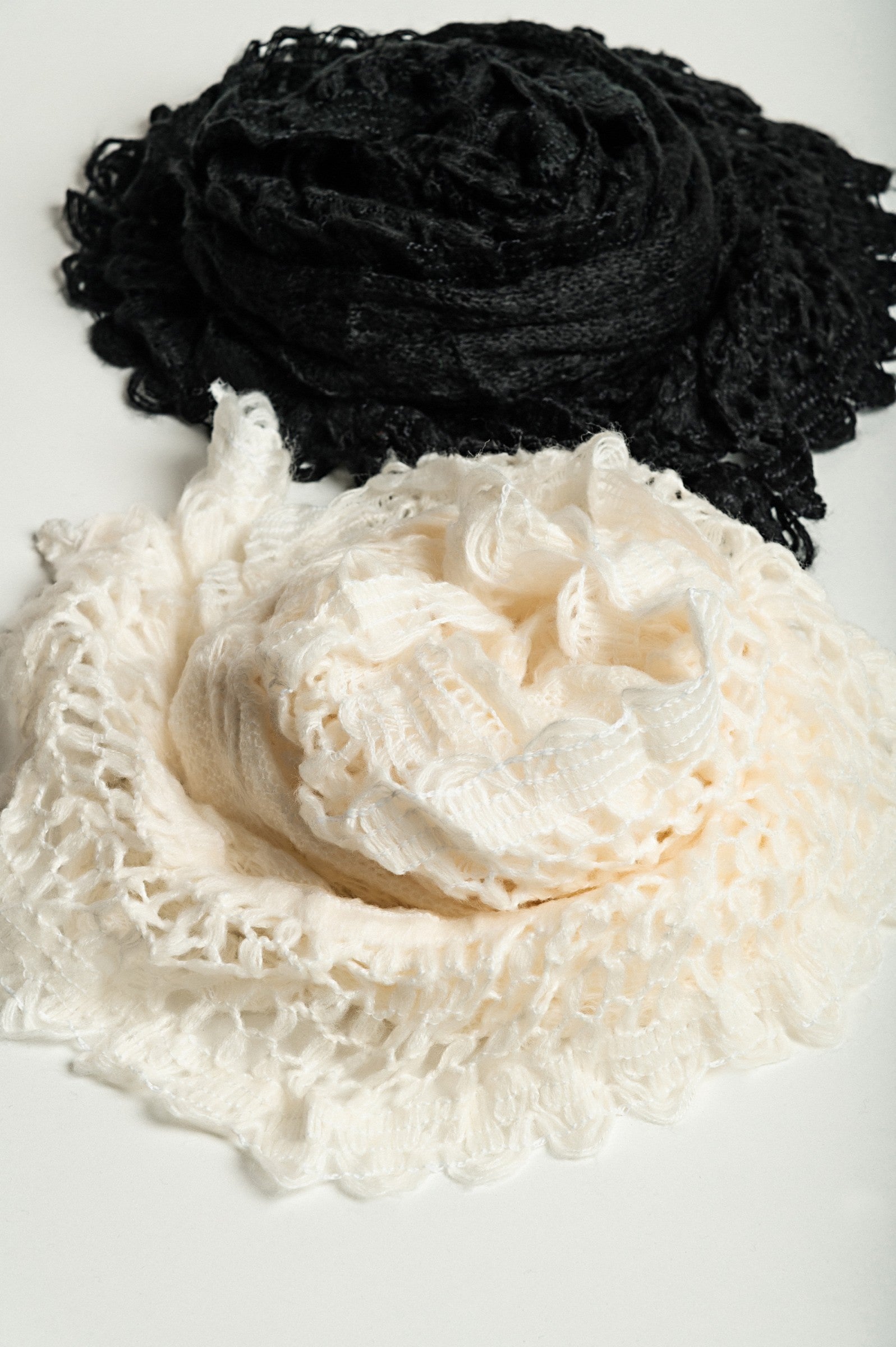 Set of 2 knitted scarves in white and black, showcasing their soft texture and stylish design.